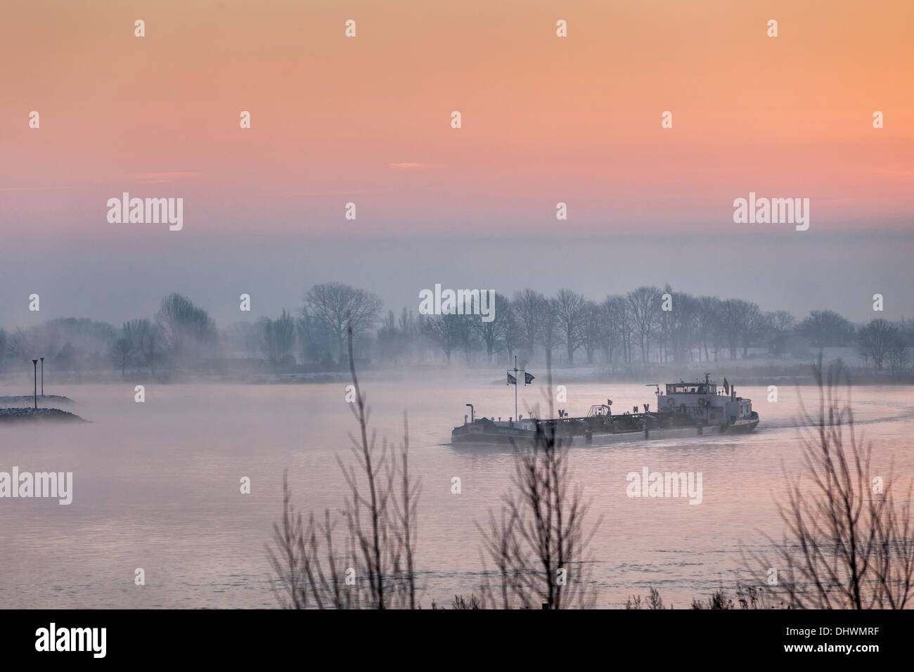 Niederlande, Lopik, Lek Fluss. Binnenschifffahrt Frachtboot. Sunrise. Winter Stockfoto