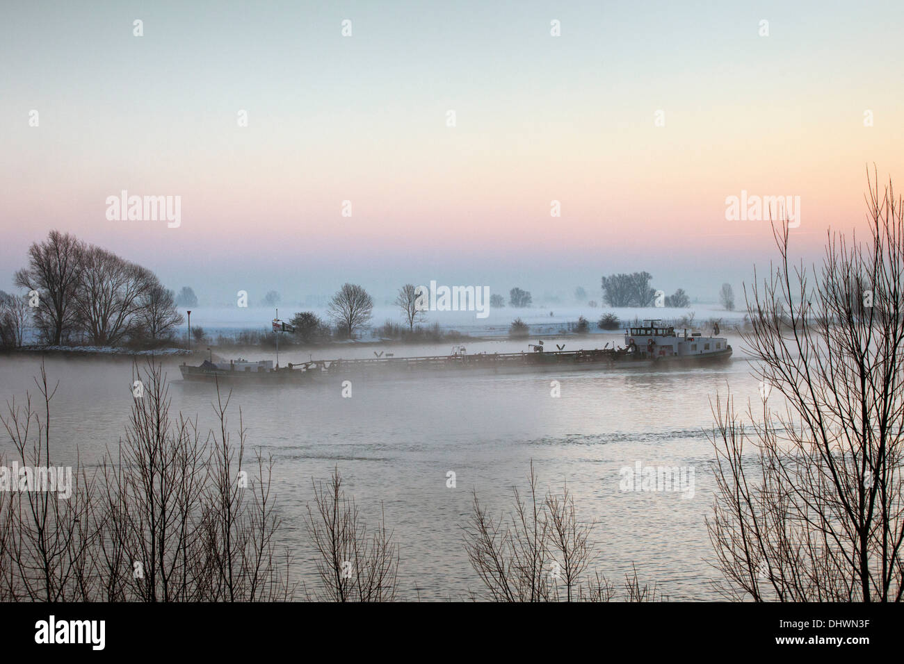 Niederlande, Lopik, Lek Fluss. Binnenschifffahrt Frachtboot. Sunrise. Winter Stockfoto