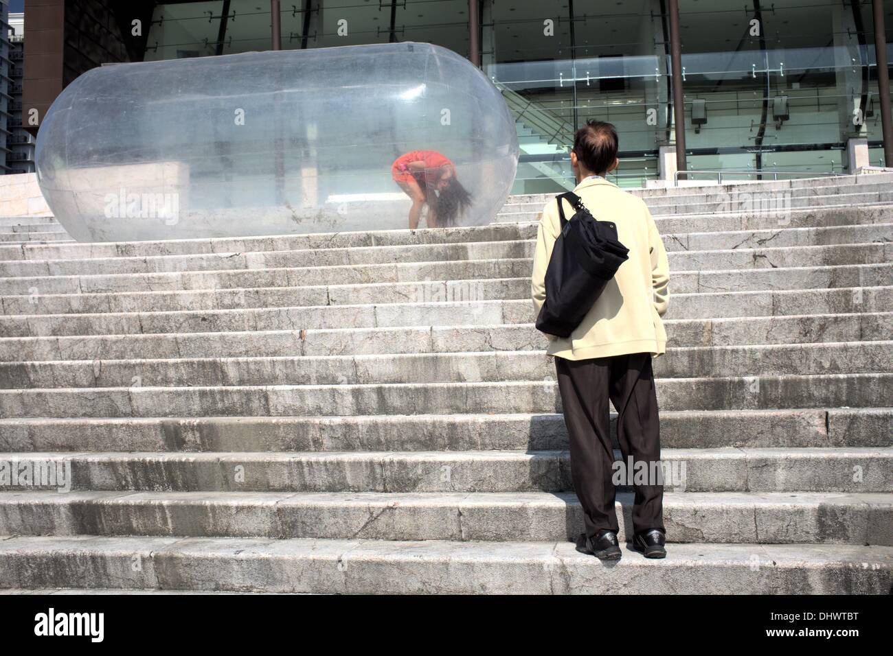 Ein Zuschauer nimmt einen genaueren Blick auf das Mädchen in der Blase beim Macau Fringe Festival Stockfoto