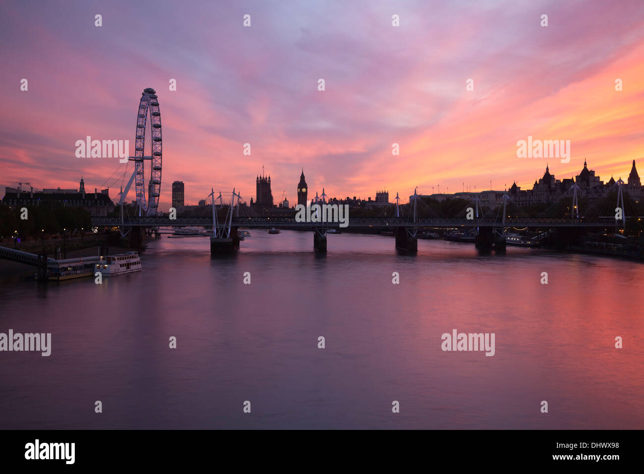 Das London Eye, Houses of Parliament und Jubilee Bridge an der Themse bei Sonnenuntergang in London, England Stockfoto