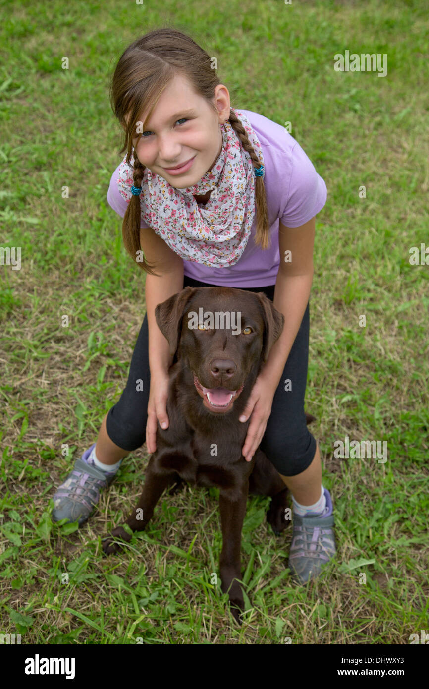Kleines Mädchen umarmen Freundin Hund auf einer Wiese Stockfoto