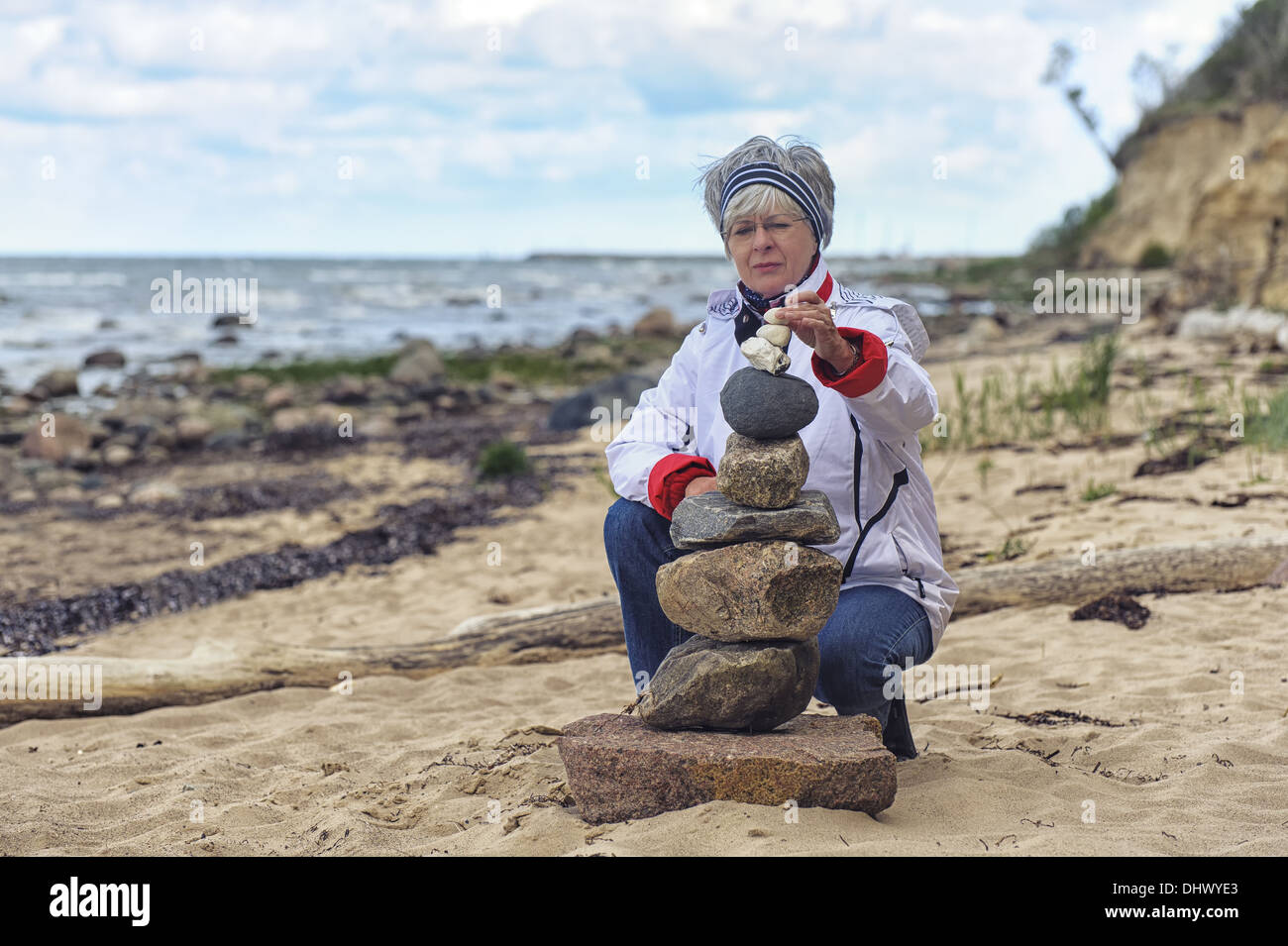 eine Frau baut ein Steinhaufen am Strand Stockfoto