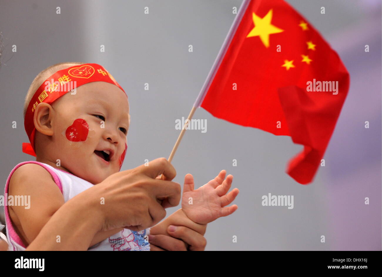 (Datei) - eine Archiv Bild, datiert 10. August 2008, zeigen Sie ein Kind winken die chinesische Flagge während der Olympischen Spiele in Peking, China. China ist zum entspannen ihre ein-Kind-Politik erklärt der chinesischen kommunistischen Partei in Peking am 15. November 2013. Foto: Bernd Thissen/dpa Stockfoto