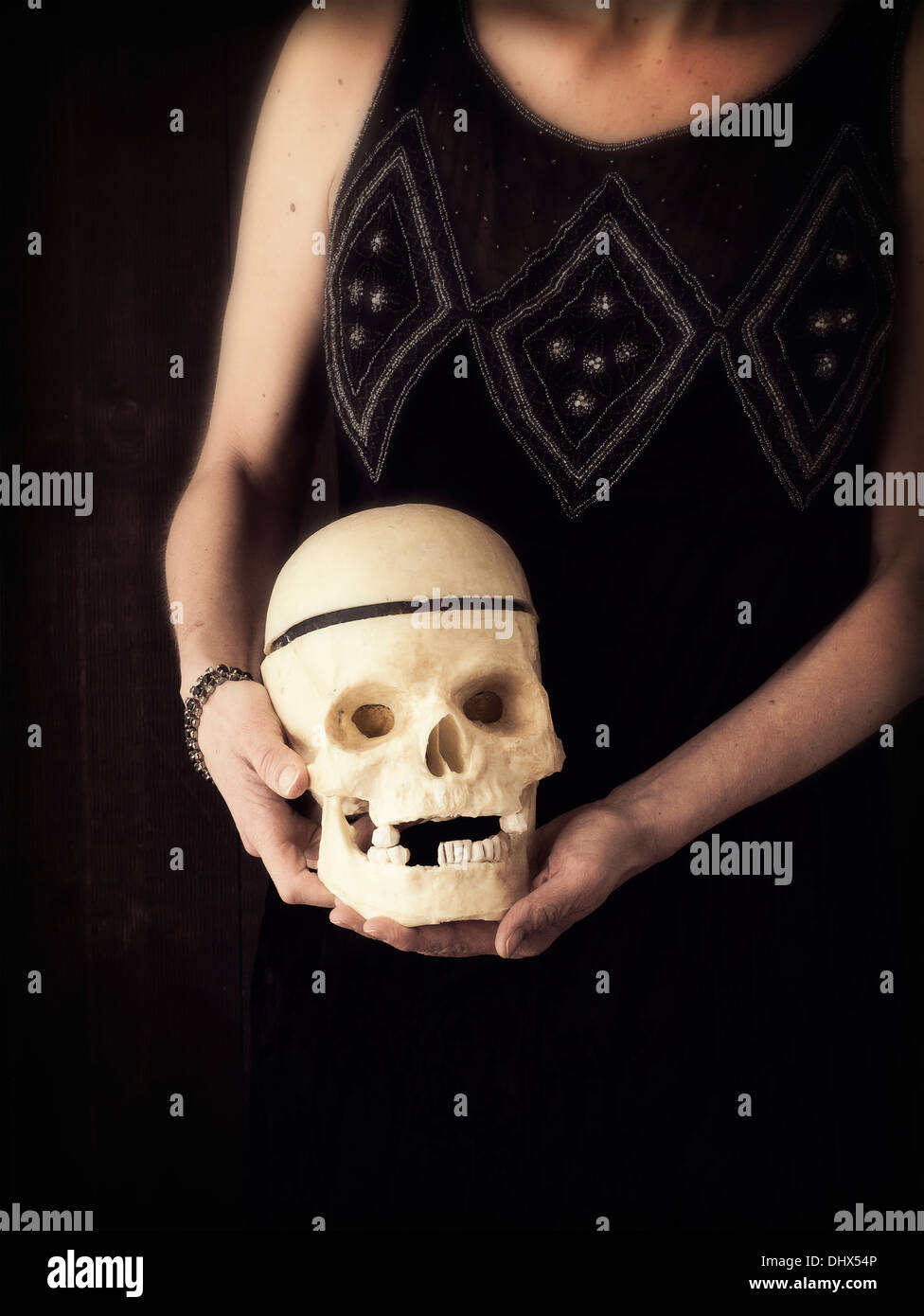 Zugeschnittenen Foto einer Frau in Vintage Flapper Kleid hält einen menschlichen Schädel. Stockfoto