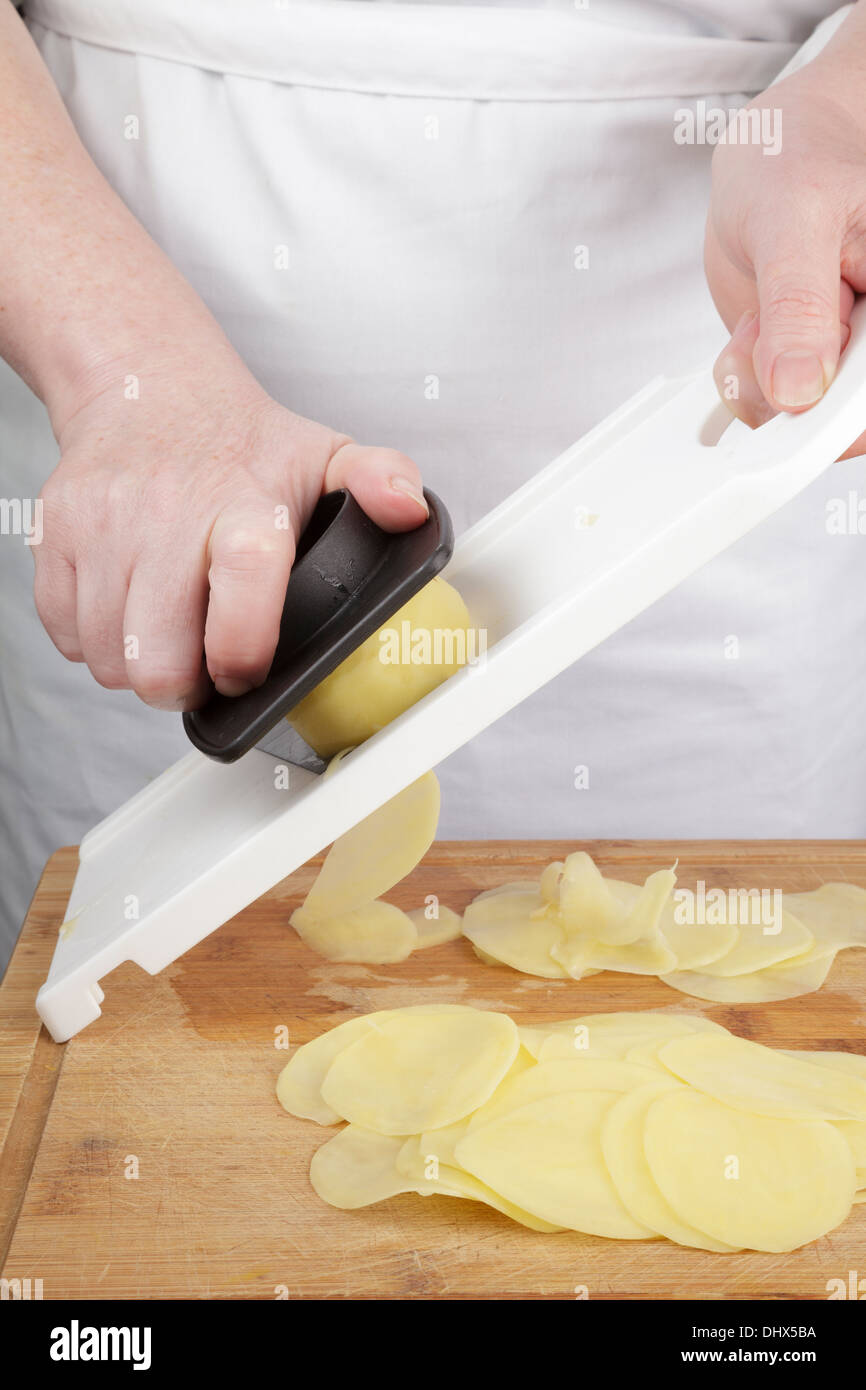 Kartoffeln schneiden mit einem Cutter Mandoline Stockfoto