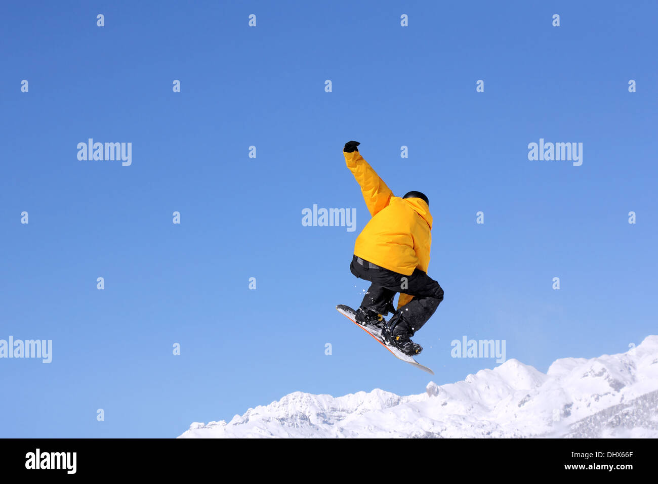 Snowboarder am Sprung im Hochgebirge am sonnigen Tag Stockfoto