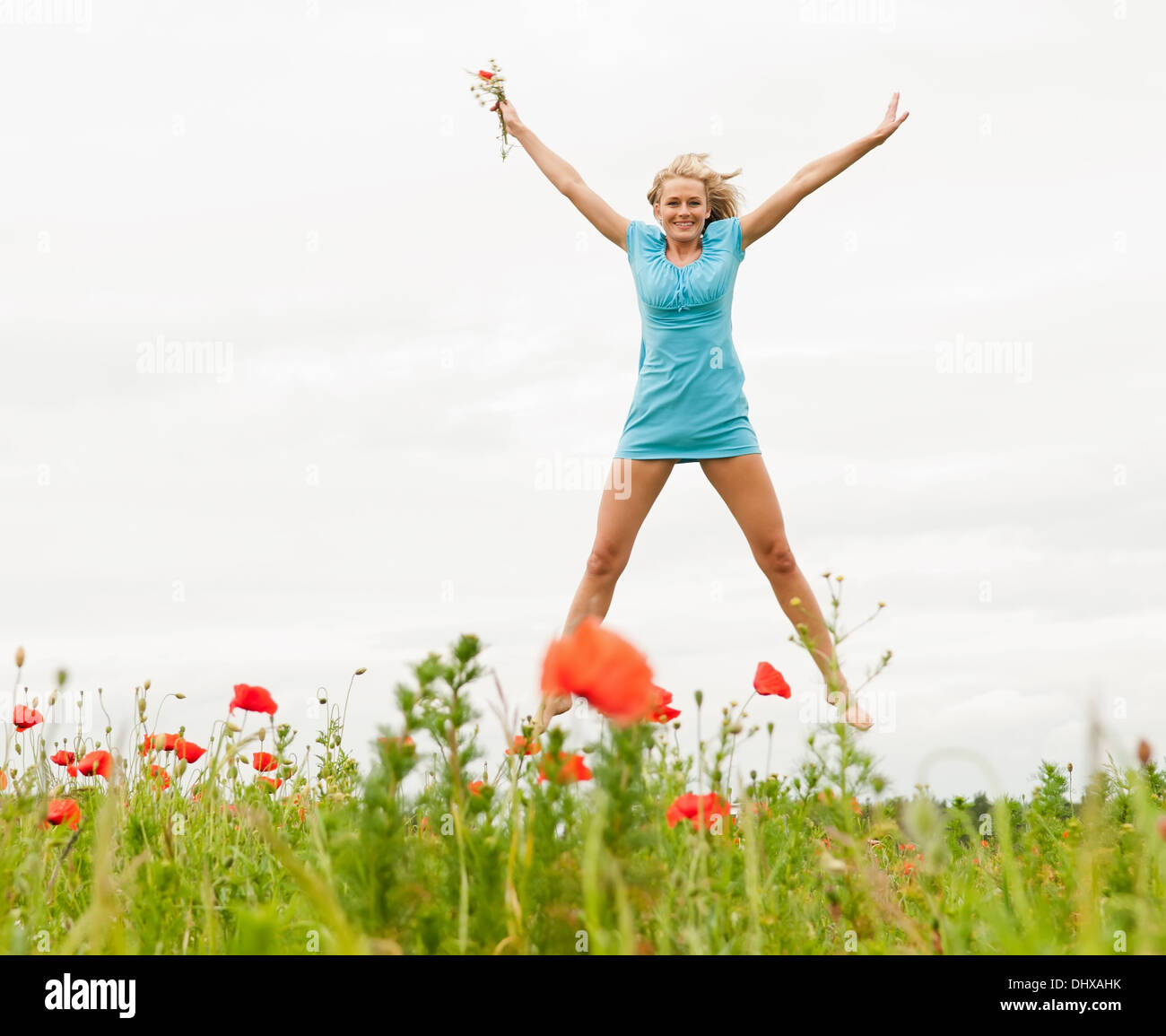 glückliche Frau springen in einem Mohnfeld Stockfoto