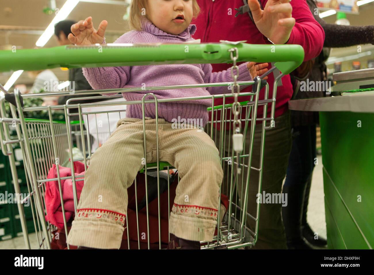 Leute, die im Supermarkt einkaufen, Kindersupermarkt-Trolley, Kind sitzt im Trolley Stockfoto