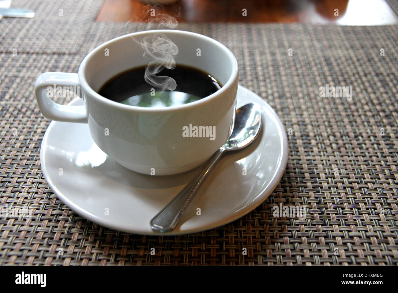 Die Nahaufnahme heißen schwarzen Kaffee in eine weiße Tasse auf den Tisch und haben Rauch aus. Stockfoto
