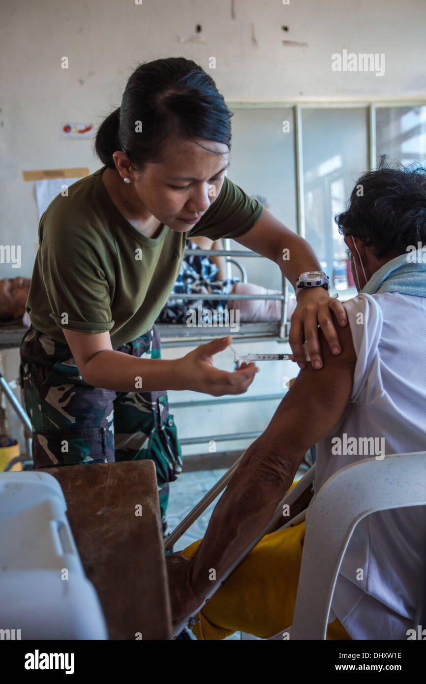 Einen medizinischen Dienstleister mit der philippinischen Armee injiziert Medizin in einer lokalen Filipino in behelfsmäßigen Krankenhaus an der Tacloban Stockfoto