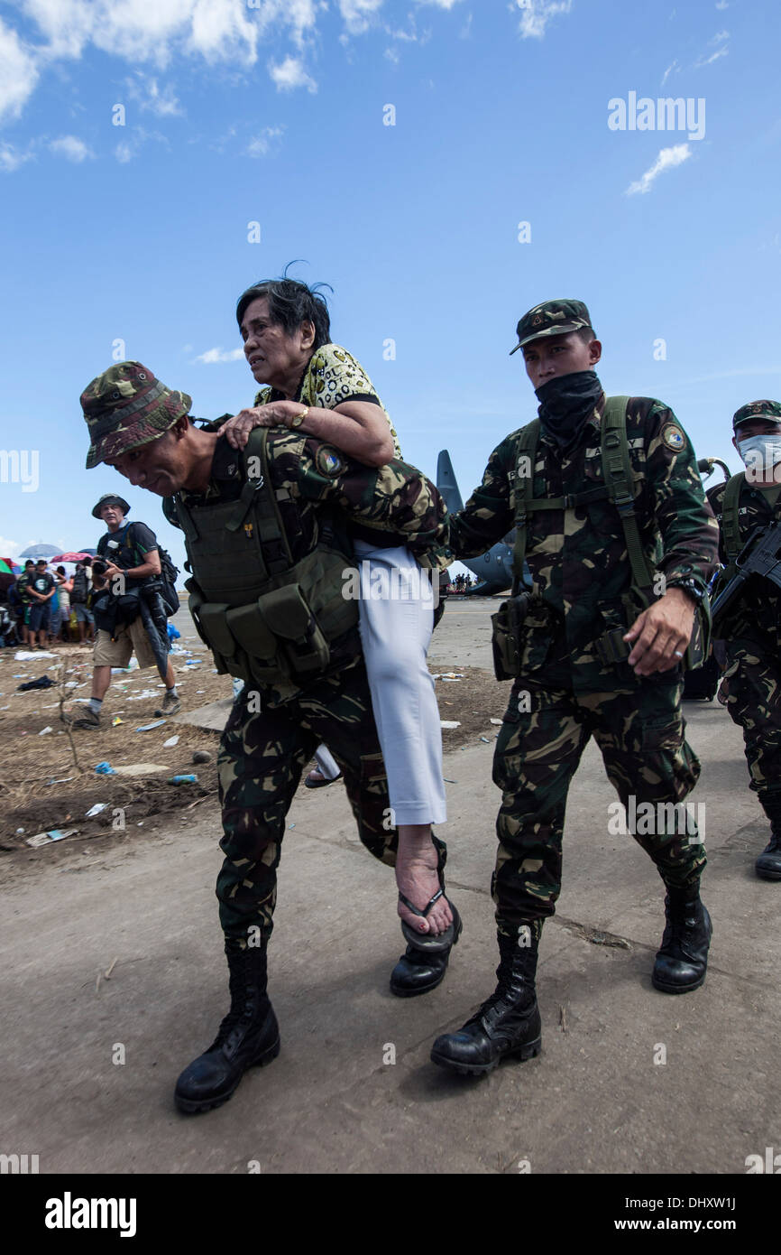 Soldaten mit der philippinischen Armee helfen eine ältere Filipino lokale zu einem wartet auf Flugzeug für den Transport nach Manila zu Stockfoto