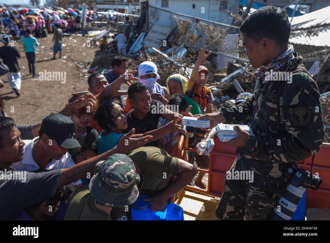 Ein Fotograf mit der philippinischen Luftwaffe händigt Packungen Kekse Vertriebenen Filipinos während sie warten, um zu manifestieren Stockfoto