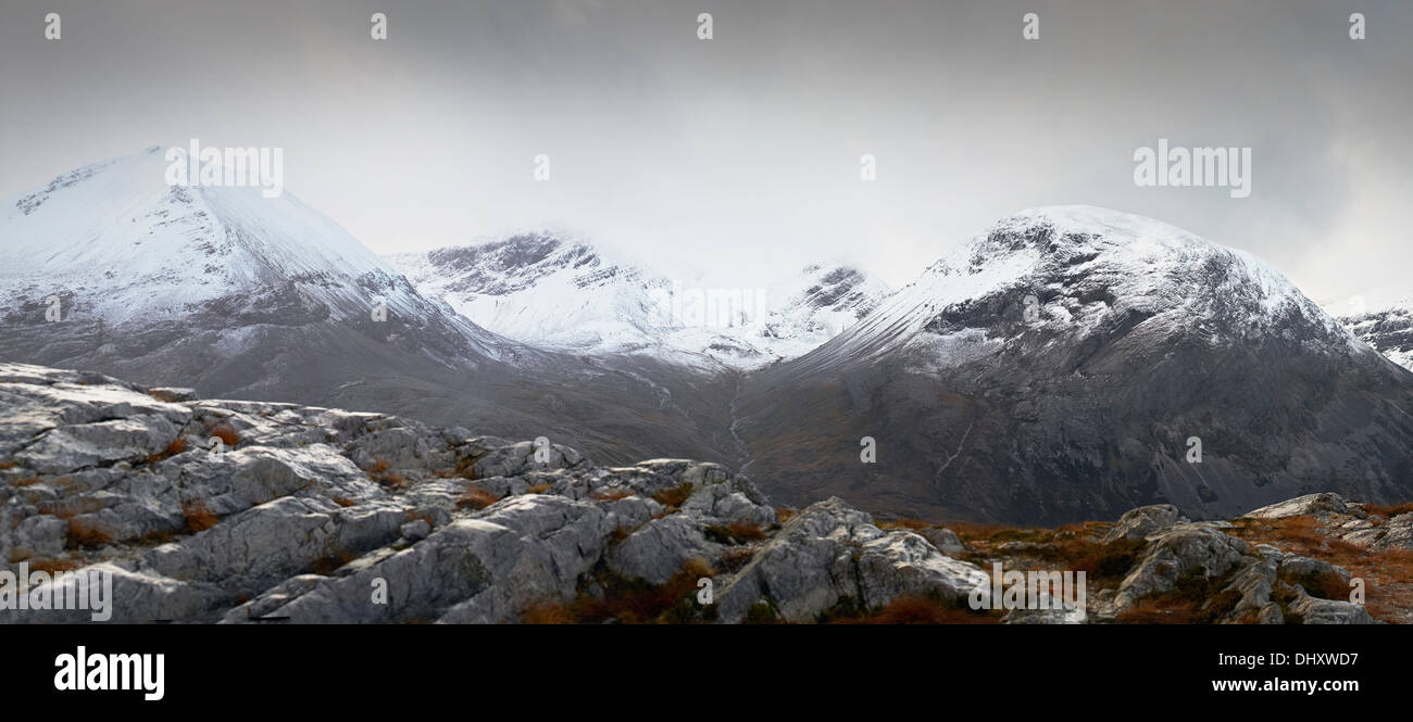 Eine Wolke und Schnee begrenzt Gipfel des Beinn Eighe in den schottischen Highlands. Stockfoto