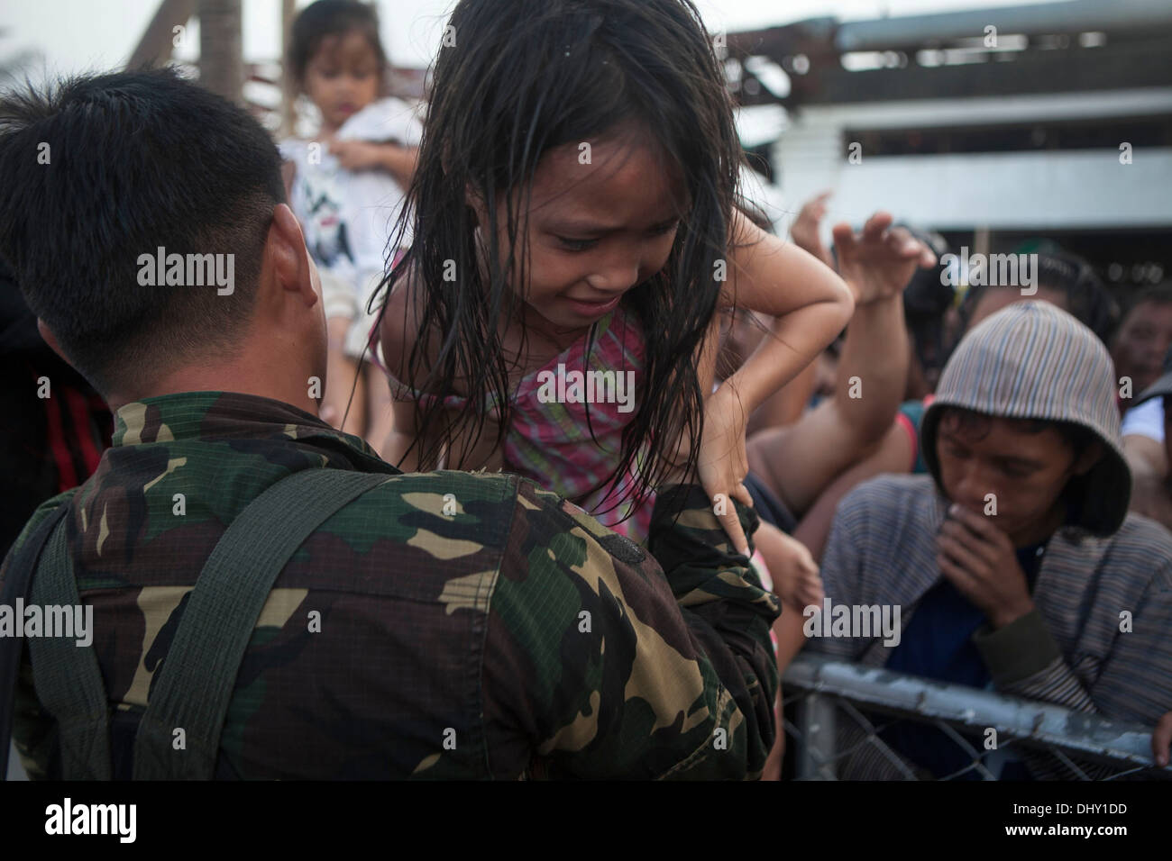 LEYTE, Republik der Philippinen – eine bewaffnete Kräfte der Philippinen Soldat hilft ein Kind über einen Zaun zu aus geflogen werden Stockfoto