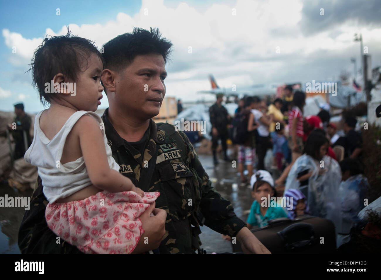 LEYTE, Republik der Philippinen – eine bewaffnete Kräfte der Philippinen Soldat hält ein Kind als ihre Familie wartet, von Tacloban Air Base im Rahmen der Operation Damayan 14 November geflogen werden. Die Regierung der Philippinen koordiniert eng mit i Stockfoto