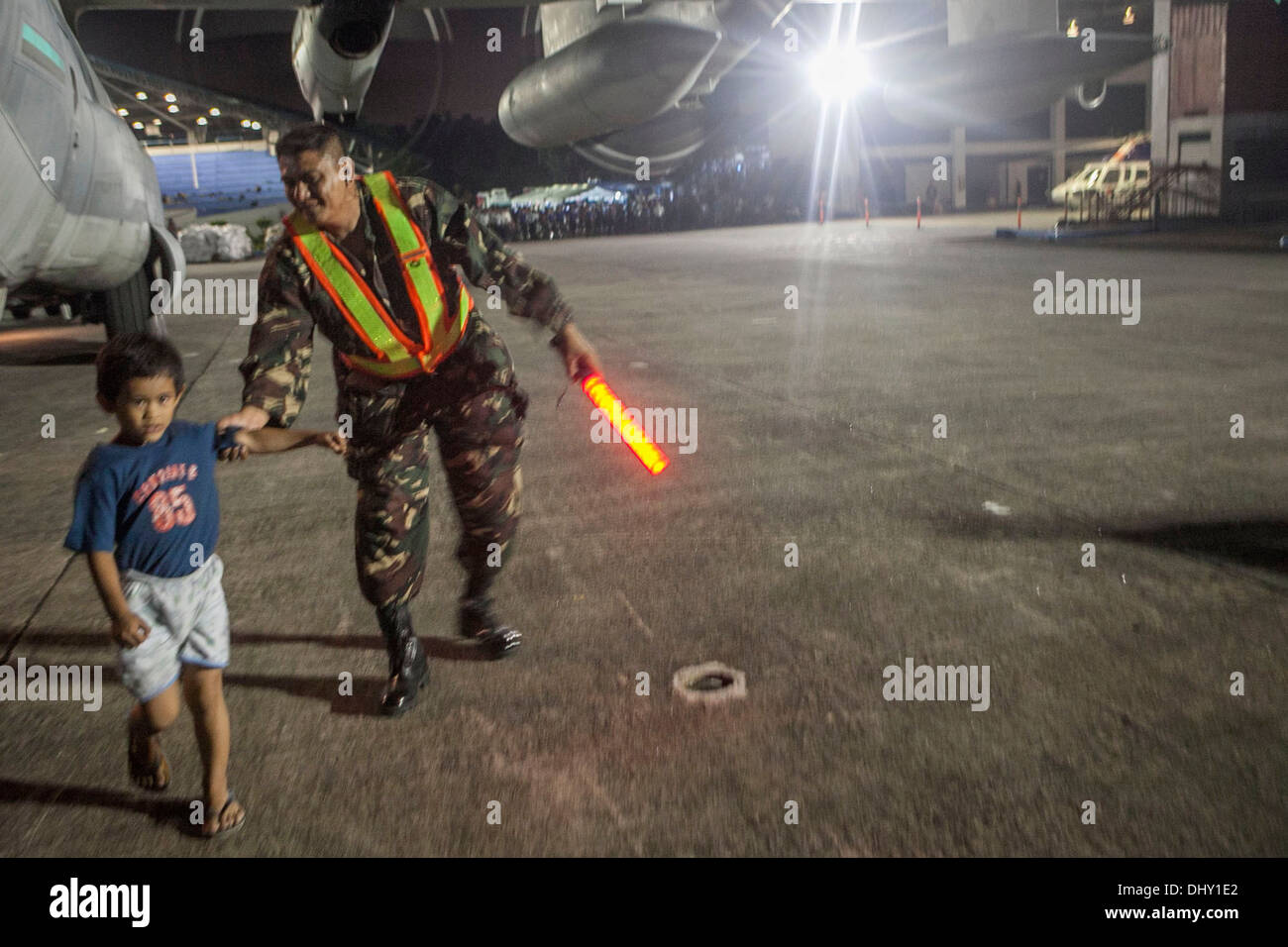 LEYTE, Republik der Philippinen – eine bewaffnete Kräfte der Philippinen Soldat hilft ein Kind vor kurzem geflogen von Tacloban Air Base aus einer c-130 Hercules aus Marine Medium Tiltrotor Squadron 262, 14 November. Die Regierung der Philippinen ist eng c Stockfoto