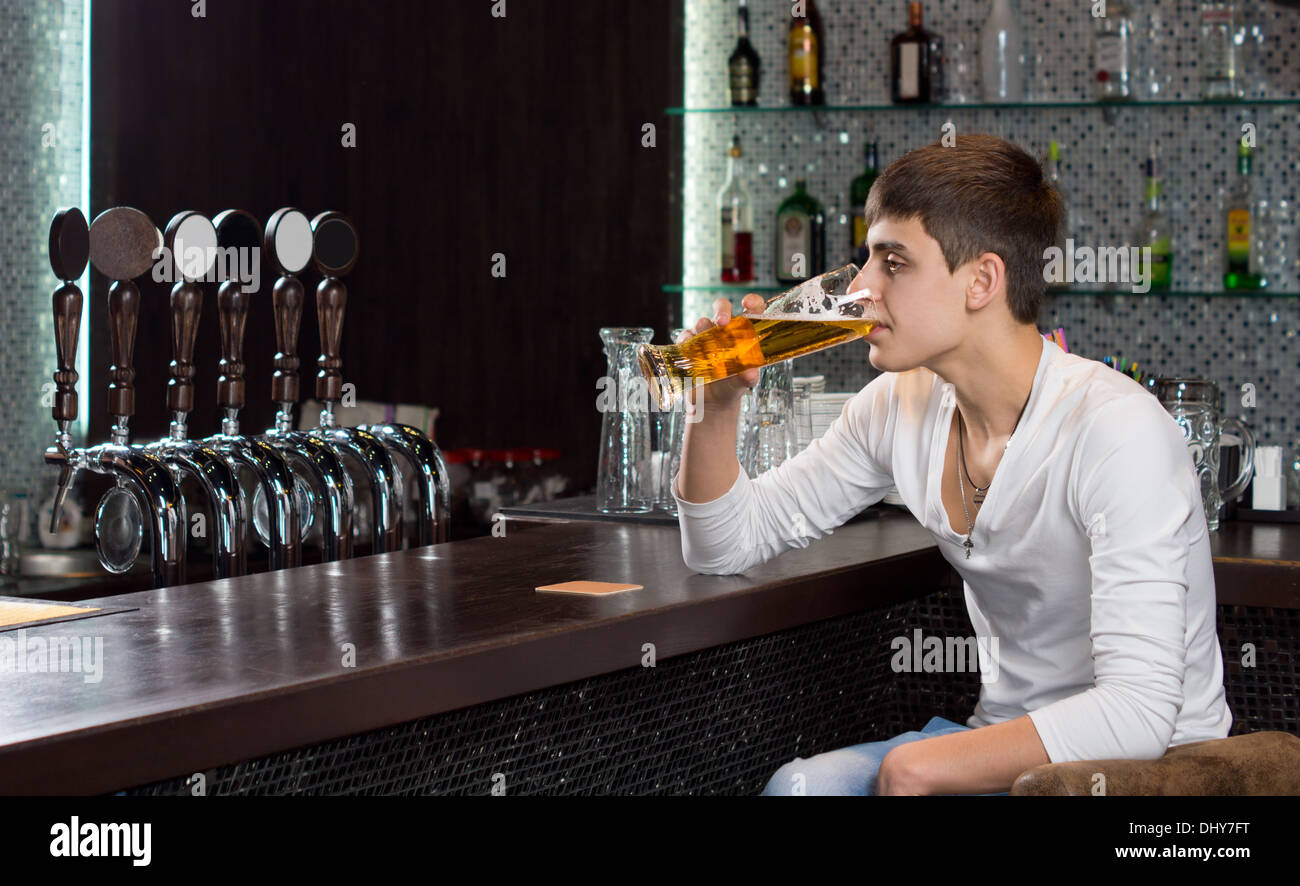Einsamer junger Mann trinken allein in der Kneipe sitzen am Ende der Bar begegnen, trinken ein kühles Bier vom Fass Stockfoto