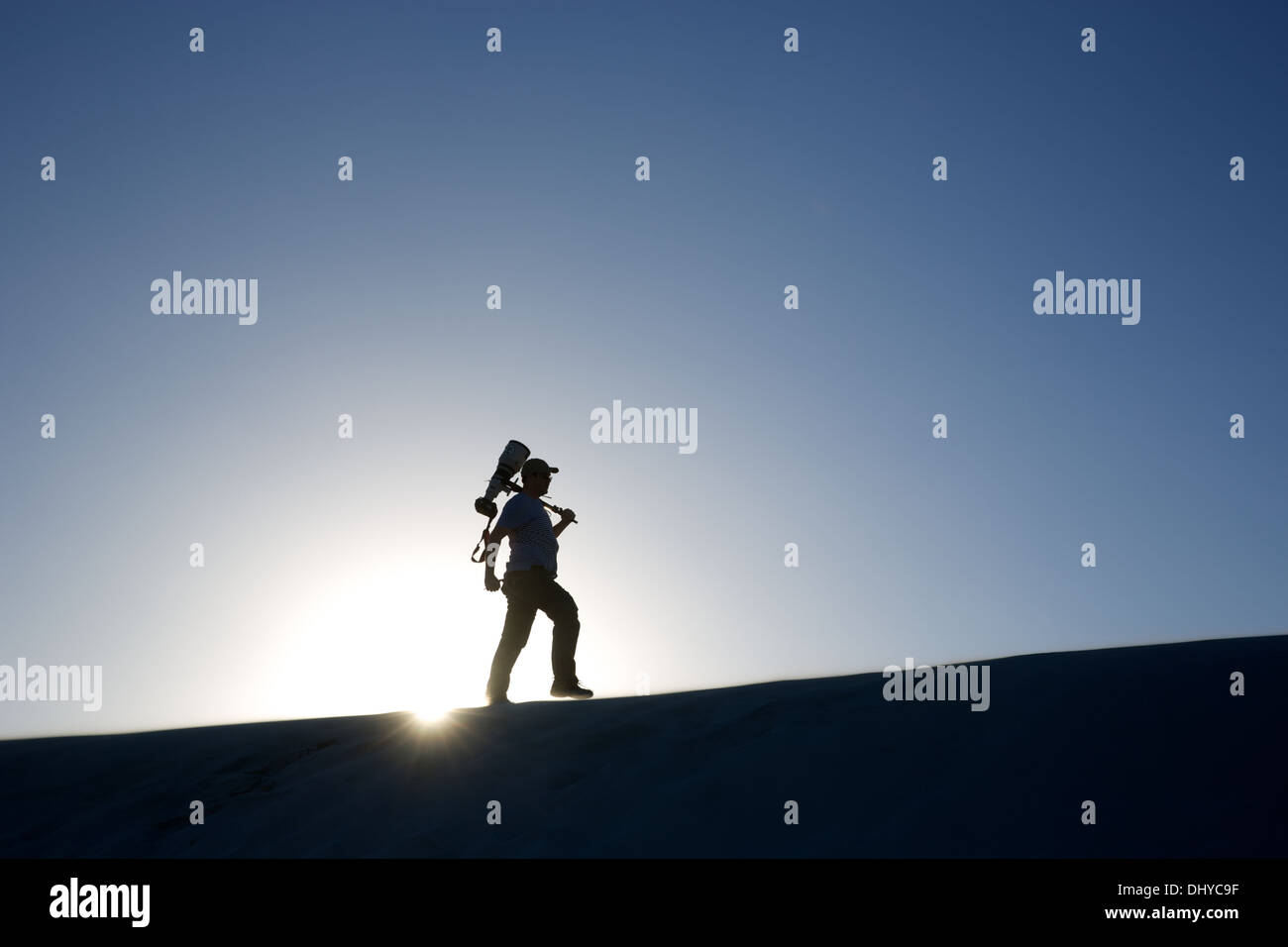 Die Silhouette eines einzigen Mannes auf einem Hügel mit einer großen Kamera und Objektiv Stockfoto