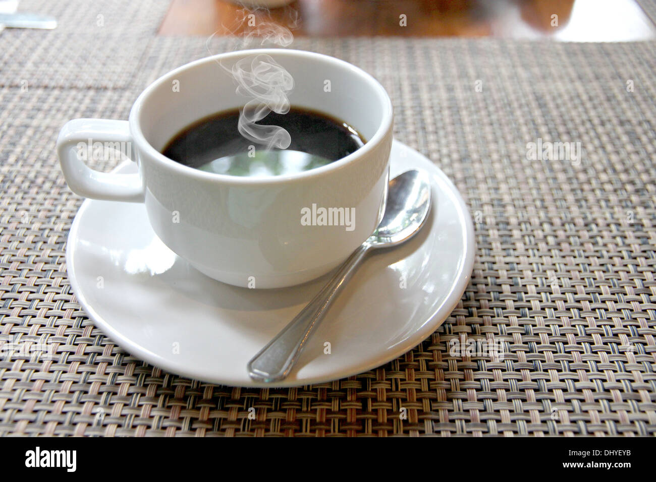 Die Nahaufnahme heißen schwarzen Kaffee in eine weiße Tasse auf den Tisch und haben Rauch aus. Stockfoto