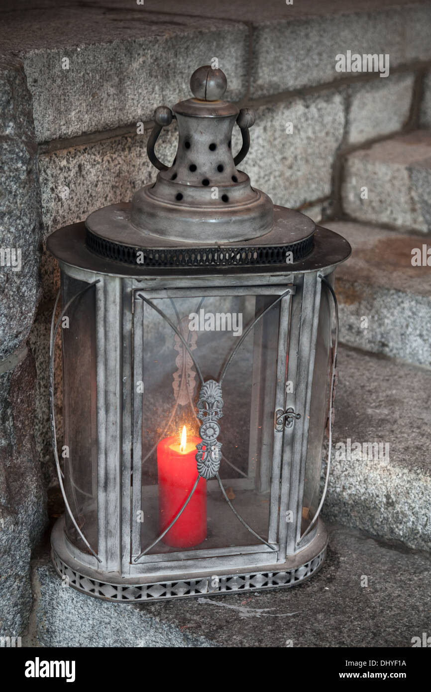 Alte Metall Außenleuchte mit roten brennenden Kerze steht auf Steintreppen Stockfoto
