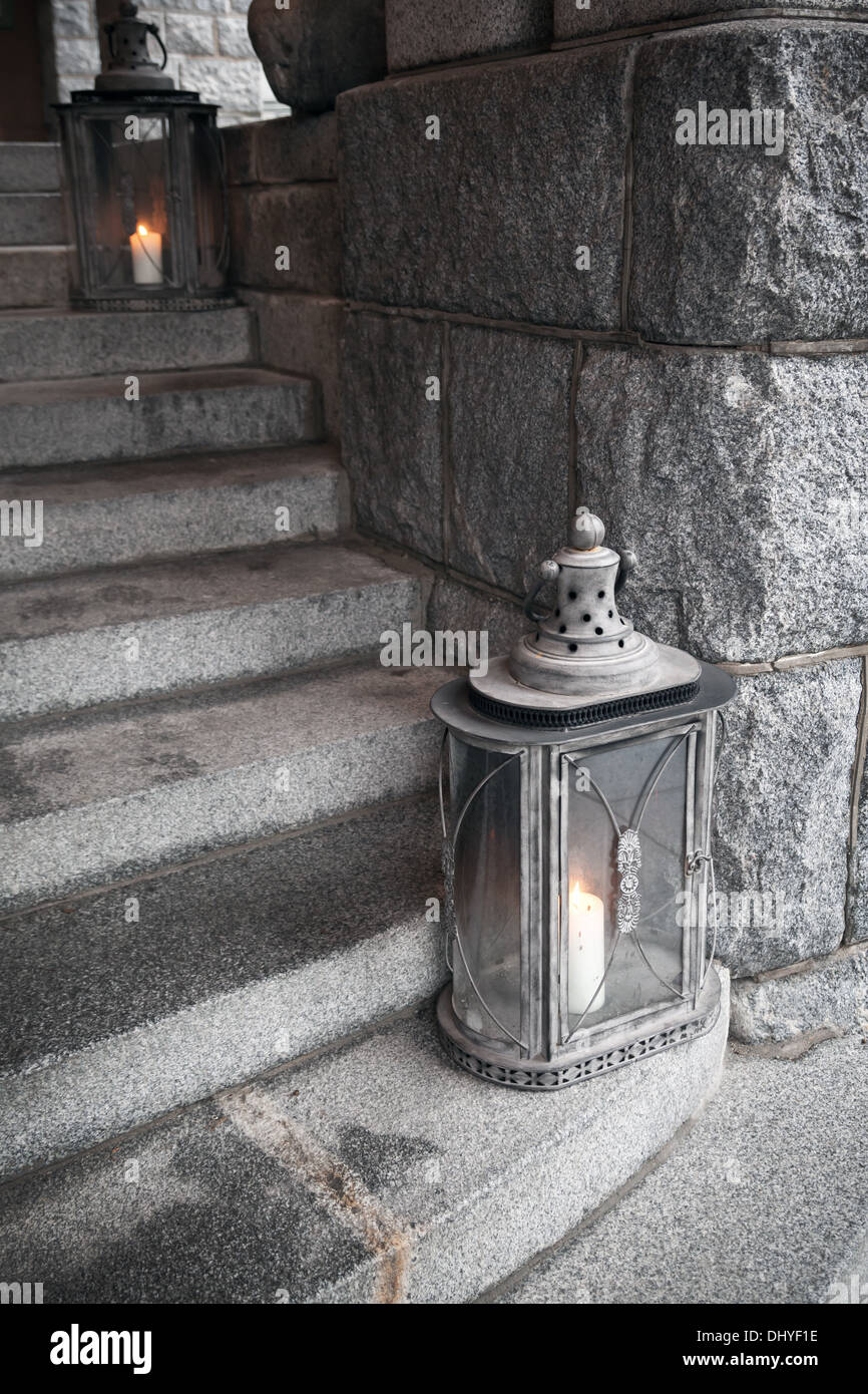 Alte Metall-Außenleuchten mit brennenden Kerzen steht über Steintreppe Stockfoto