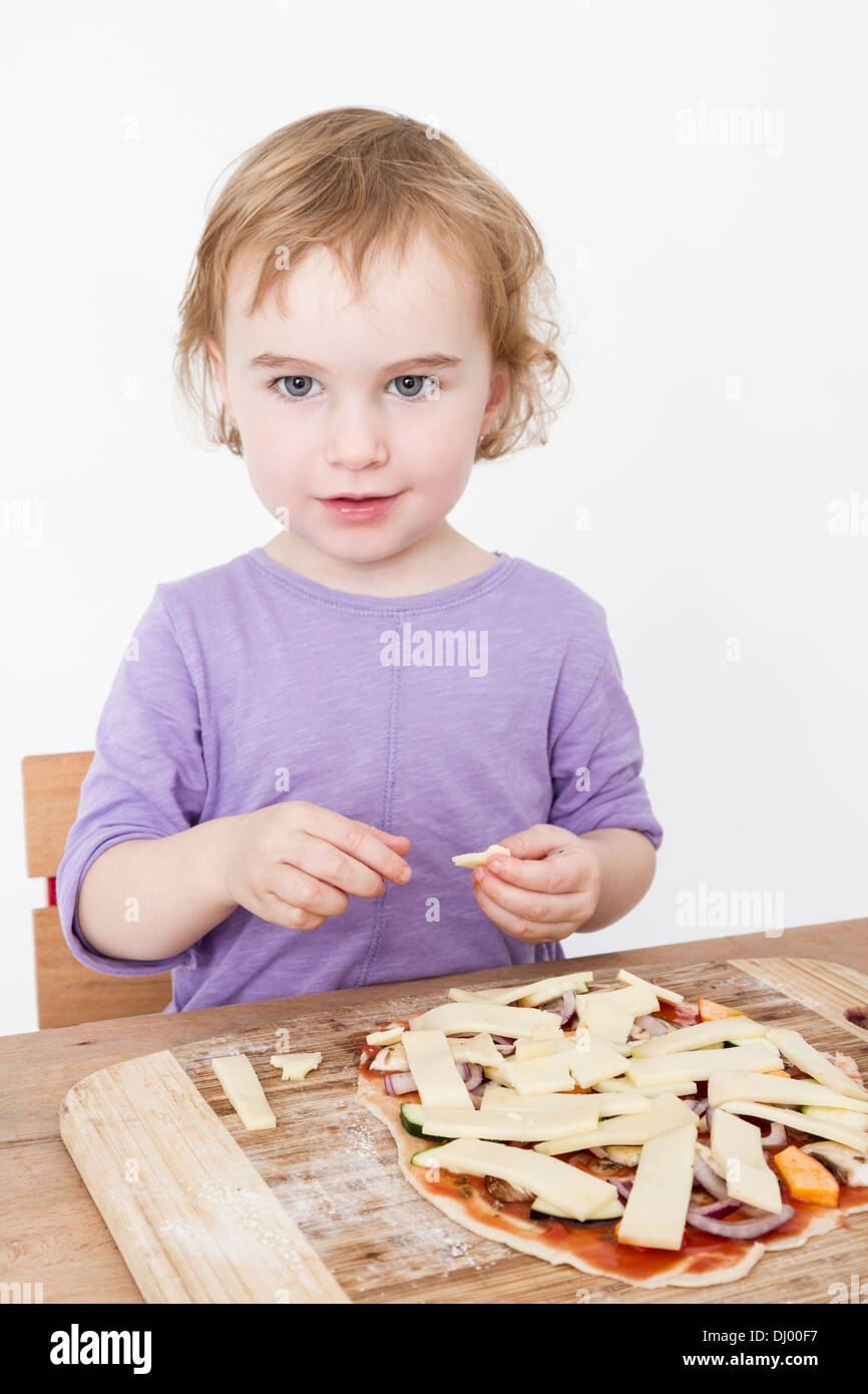 junges Kind hausgemachte Pizza Käse aufsetzen. Studio mit hellen grauen Hintergrund gedreht Stockfoto