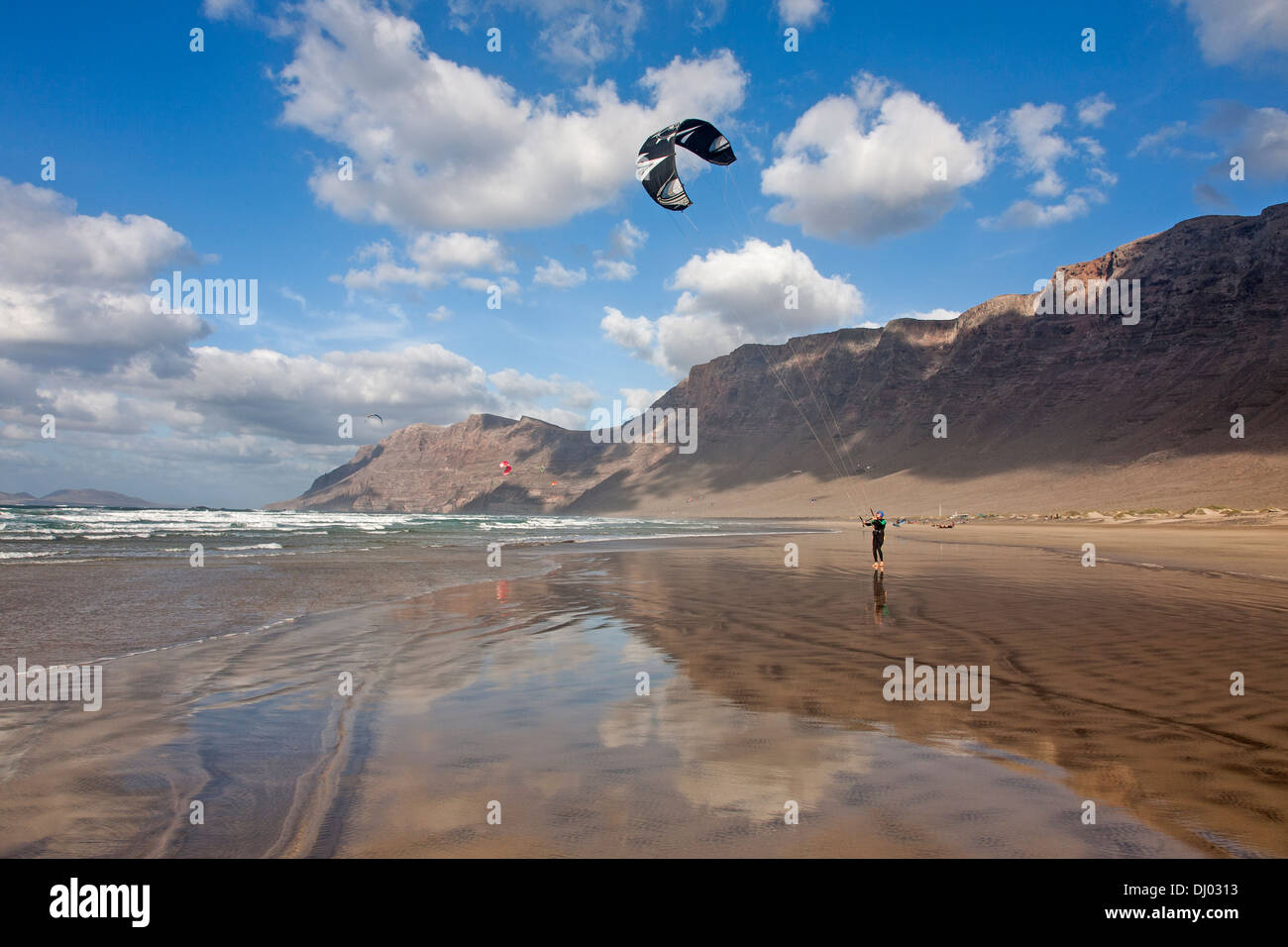 Mann-Kitesurfen auf windigen Famara Strand Risco de Famara im Hintergrund Stockfoto