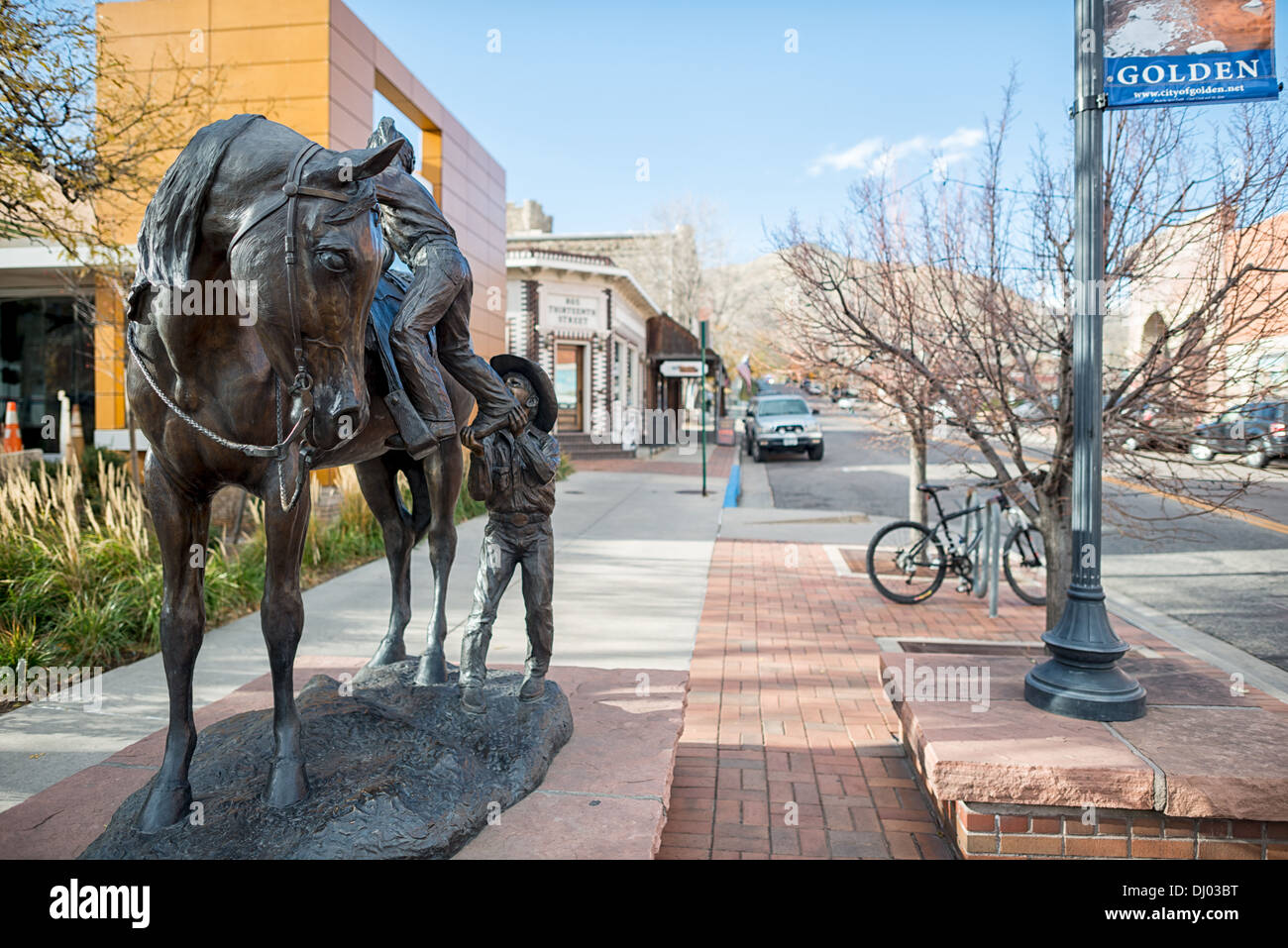 GOLDEN, Colorado – die Statue eines kleinen Jungen, der einem kleinen Mädchen beim Pferderennen in Golden, Colorado, am östlichen Rand der Rocky Mountains in Denver hilft. Das Golden Today wurde während des Pike's Peak Gold Rush gegründet und ist bekannt für sein reiches Erbe, Outdoor-Aktivitäten und den Geburtsort der Coors Brewery, die eine einzigartige Mischung aus Geschichte, Kultur und natürlicher Schönheit verkörpert. Stockfoto