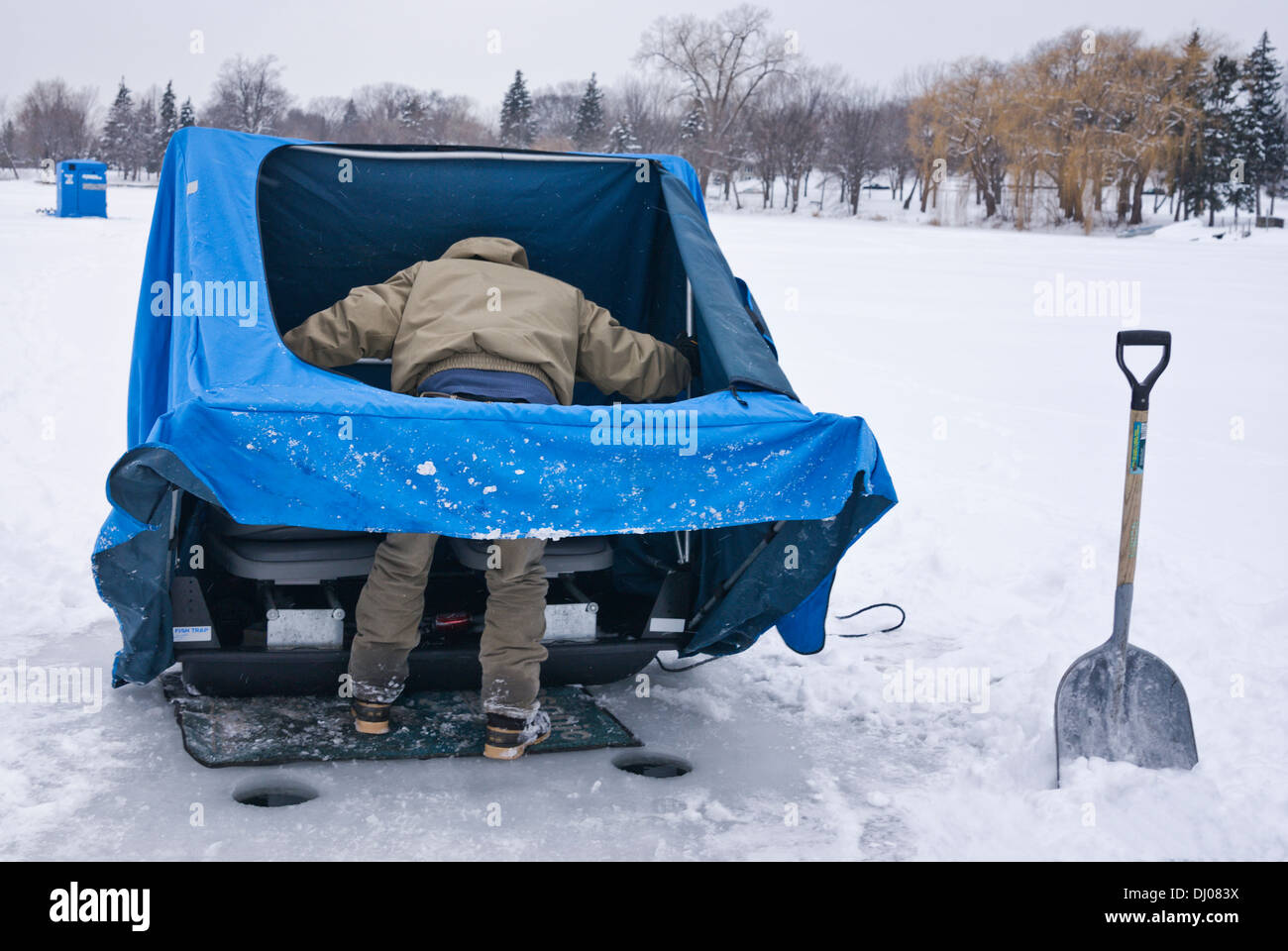 Mann nimmt seine blaue Eis Fischerhütte auf einem zugefrorenen See, Minneapolis, Minnesota, USA Stockfoto