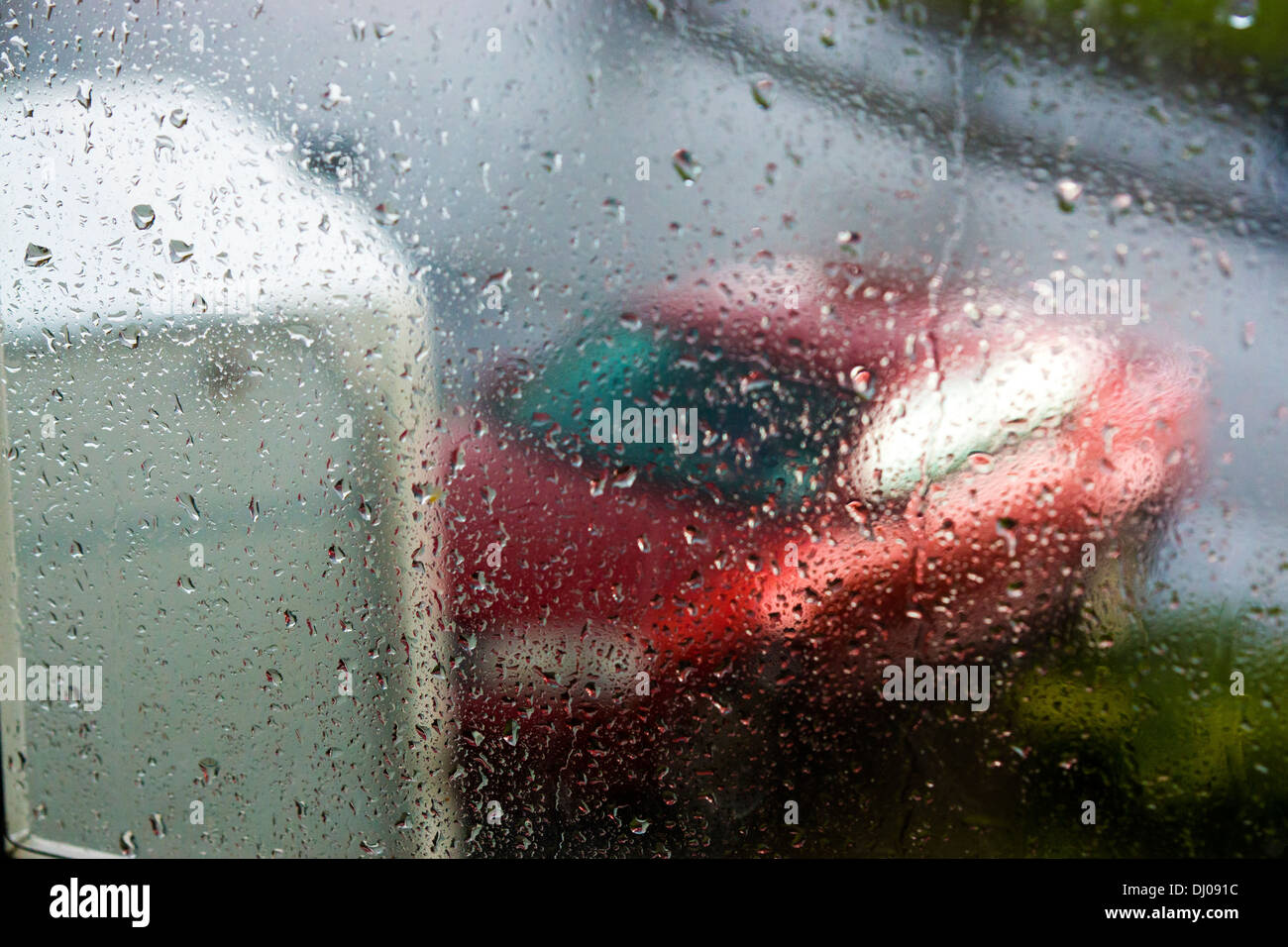 rotes Auto Wohnwagen Regen Fenster Wasser Rasen Straße nass Stockfoto