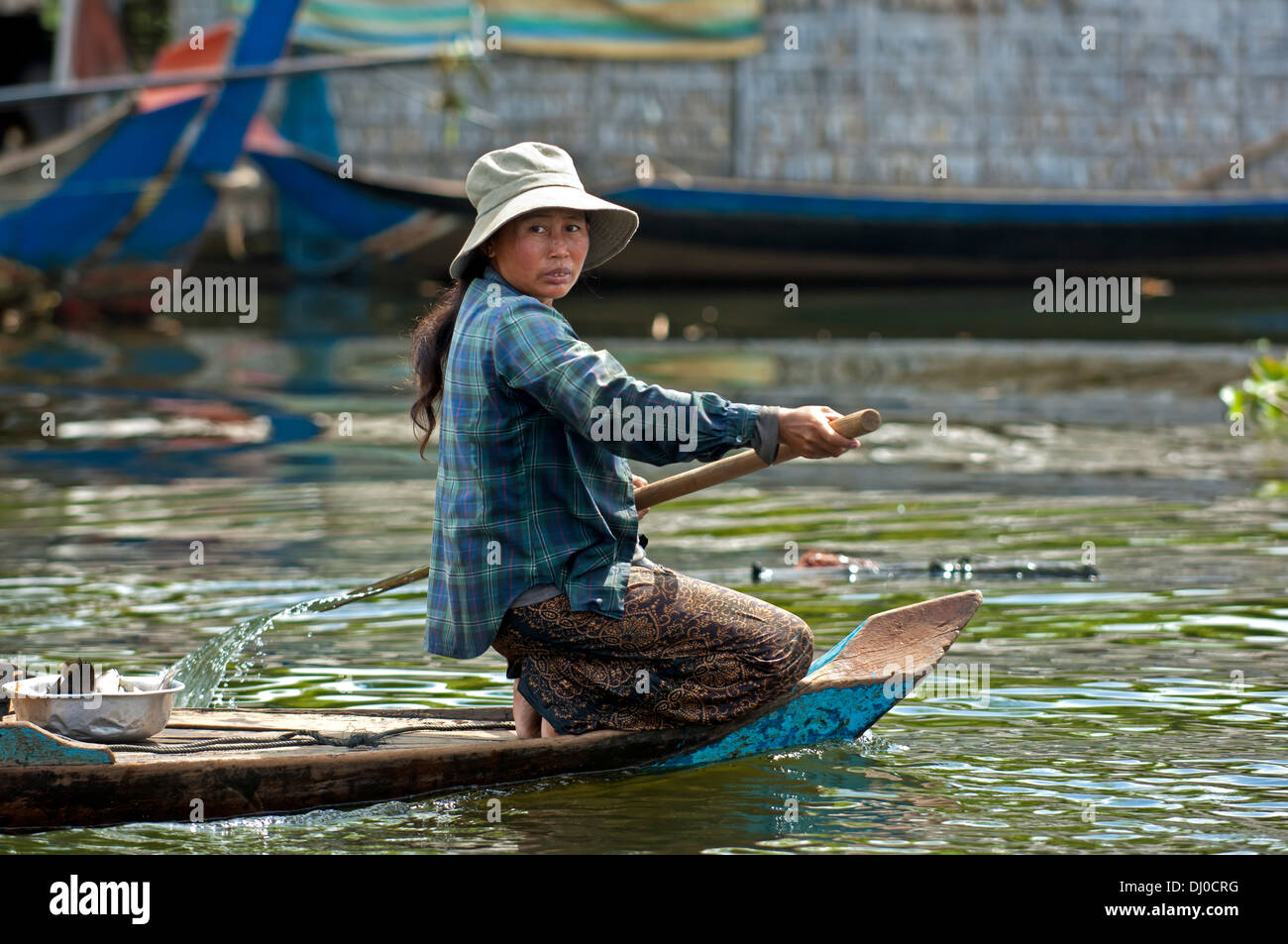 Kniende Frau paddeln in einem Boot auf dem Tonle Sap See, Kambodscha Stockfoto