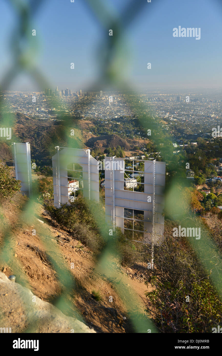 Hollywood-Schild, gesehen von hinten durch eine Kette link Zaun, LA Stadt in der Ferne unten Stockfoto