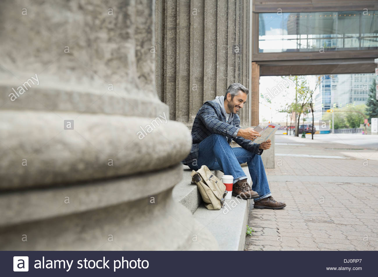 Mann sitzt auf Schritte Blick auf Karte Stockfoto
