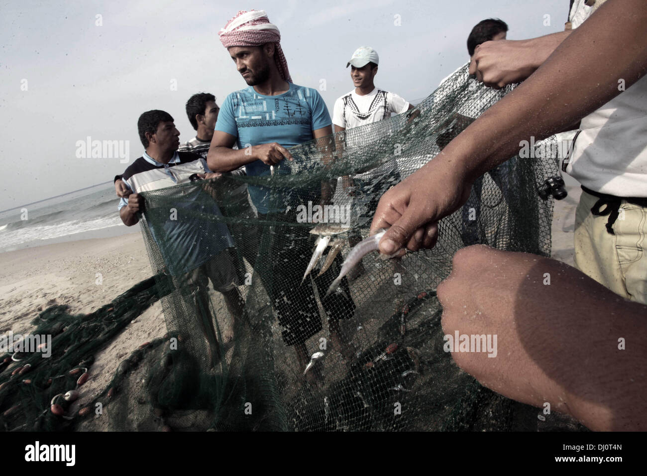 18. November 2013 - Gaza-Stadt, Gazastreifen, Palästina - palästinensische Fischer sammeln Fische aus ihrem Netz am Strand von Gaza-Stadt, am 18. November 2013. Israel beschränkt die Fischereizone auf drei Seemeilen nach der Entführung des israelischen Soldaten Gilad Shalit im Jahr 2007. Die Oslo-Abkommen 1993 mit der palästinensischen Autonomiebehörde unterzeichneten besagen, dass Gaza s Fischereizone auf 20 Seemeilen auszudehnen. Die Zone wurde dann erweitert auf sechs Seemeilen als Bestandteil der ägyptischen vermittelten Waffenstillstand im November 2012, aber Israel zeitweise reduzieren auf drei Seemeilen jedes tim Stockfoto