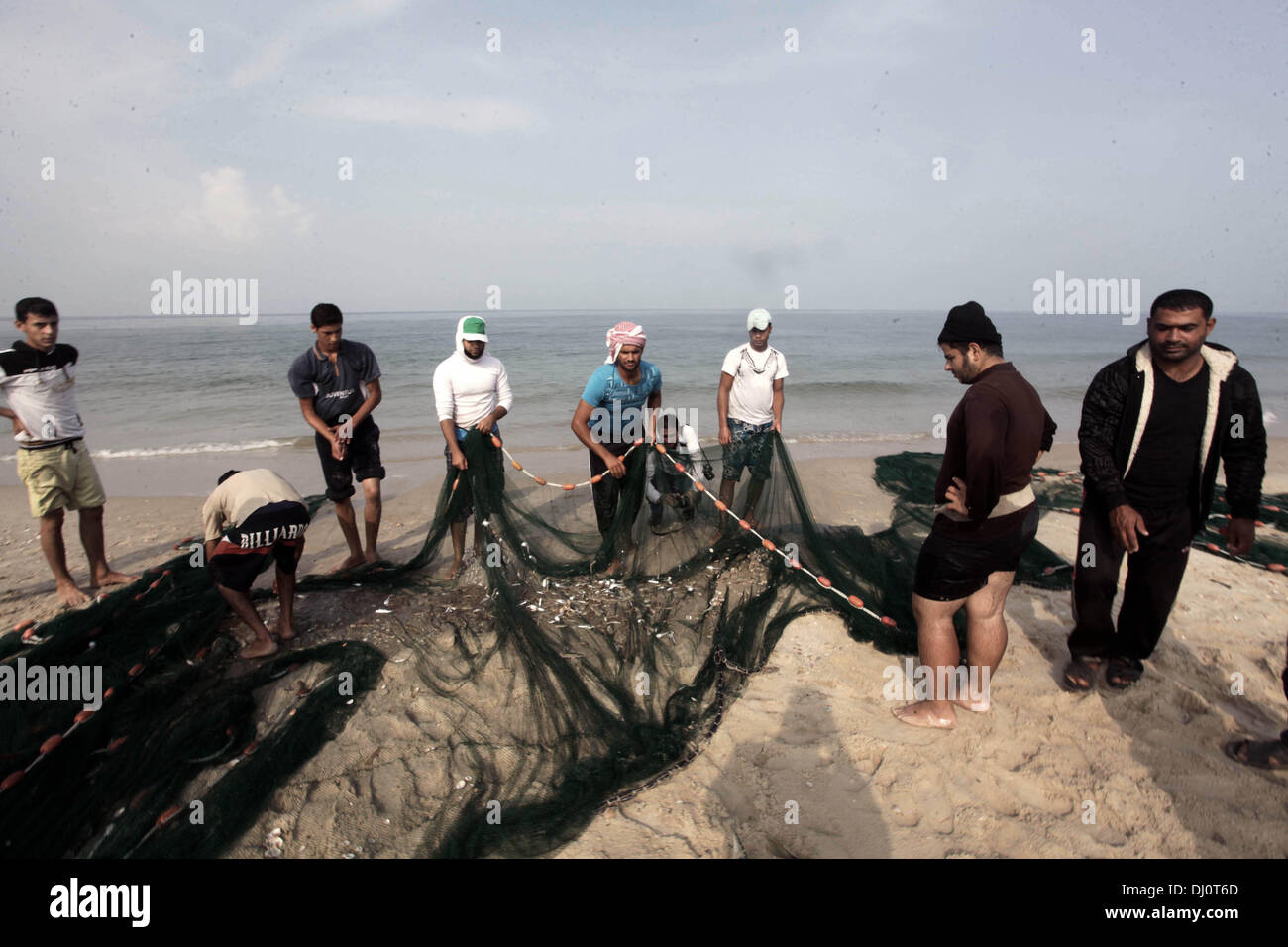 18. November 2013 - Gaza-Stadt, Gazastreifen, Palästina - palästinensische Fischer sammeln Fische aus ihrem Netz am Strand von Gaza-Stadt, am 18. November 2013. Israel beschränkt die Fischereizone auf drei Seemeilen nach der Entführung des israelischen Soldaten Gilad Shalit im Jahr 2007. Die Oslo-Abkommen 1993 mit der palästinensischen Autonomiebehörde unterzeichneten besagen, dass Gaza s Fischereizone auf 20 Seemeilen auszudehnen. Die Zone wurde dann erweitert auf sechs Seemeilen als Bestandteil der ägyptischen vermittelten Waffenstillstand im November 2012, aber Israel zeitweise reduzieren auf drei Seemeilen jedes tim Stockfoto