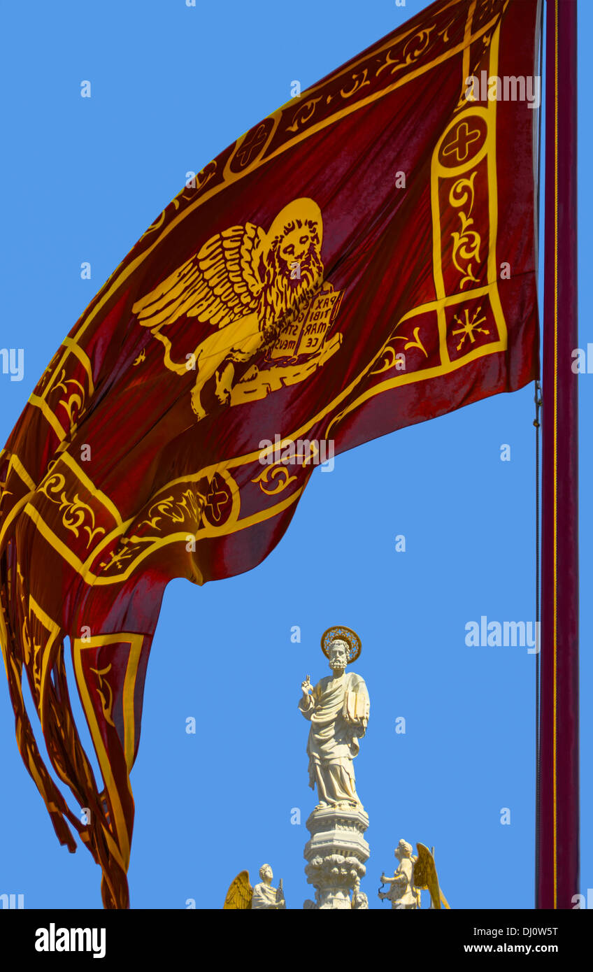 Statue des Heiligen Markus, am Markusdom in Venedig mit der venezianischen Flagge im Vordergrund. Stockfoto