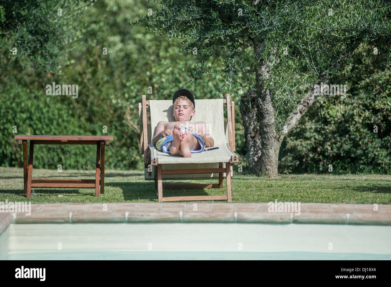 Ein Junge befindet sich ein Schwimmbad, das Anhören von Musik Stockfoto