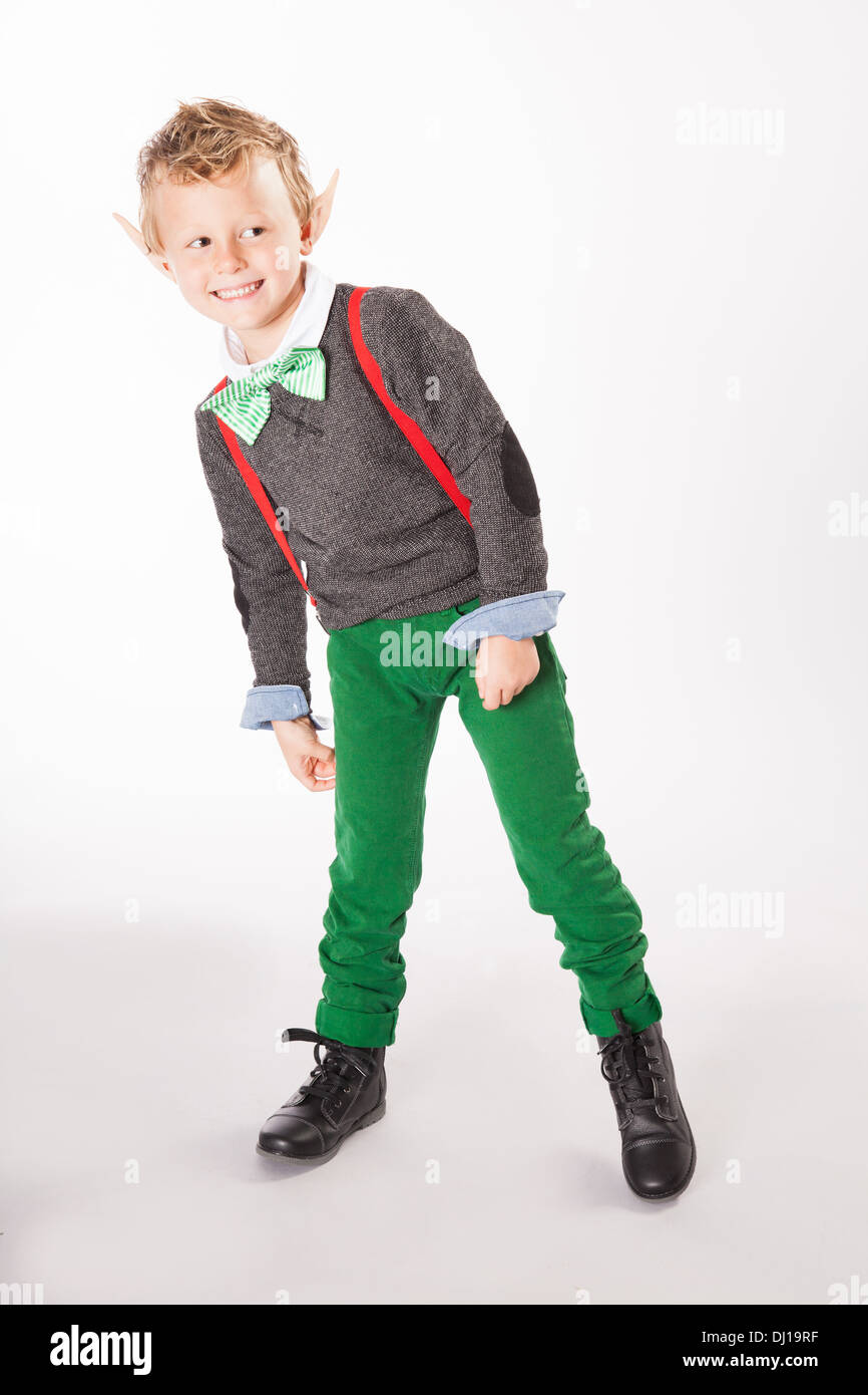 Ein kleiner Junge gekleidet in ein Weihnachtsmann Elfe Kostüm späht hinter der Kamera Stockfoto