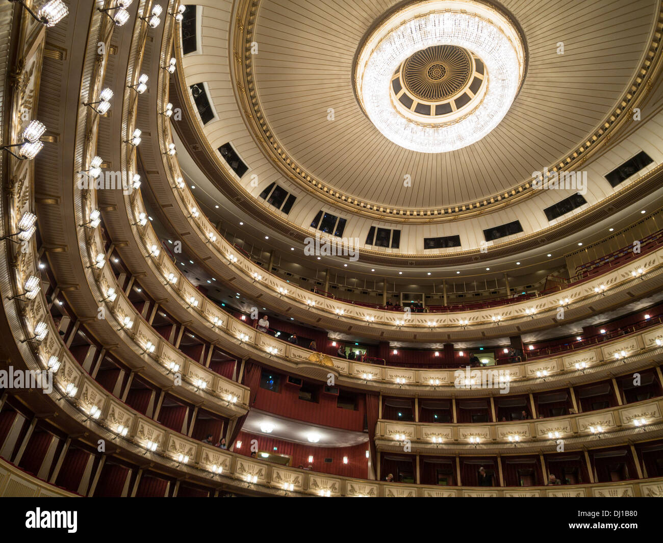 Decke und Balkone der Haupthalle an der Wiener Staatsoper. Ein großer Kronleuchter dominiert den kreisförmigen Raum. Stockfoto