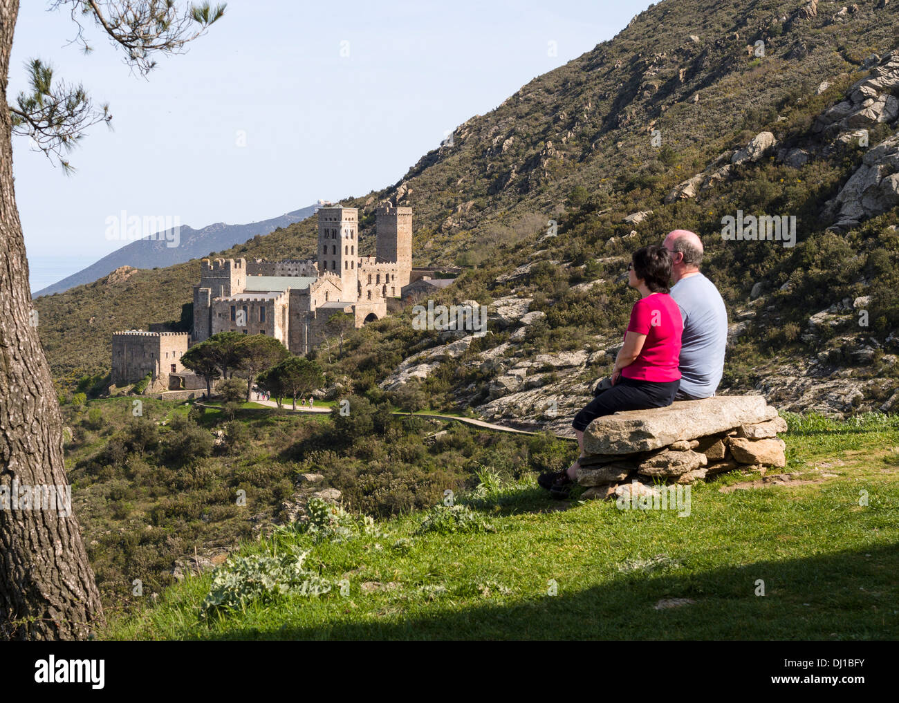 Bewundern Sie die Aussicht. Ein paar sitzt auf einer Steinbank und bewundert die Aussicht über die Hügel und vorbei an das Kloster Sant Pere de Rodes. Stockfoto