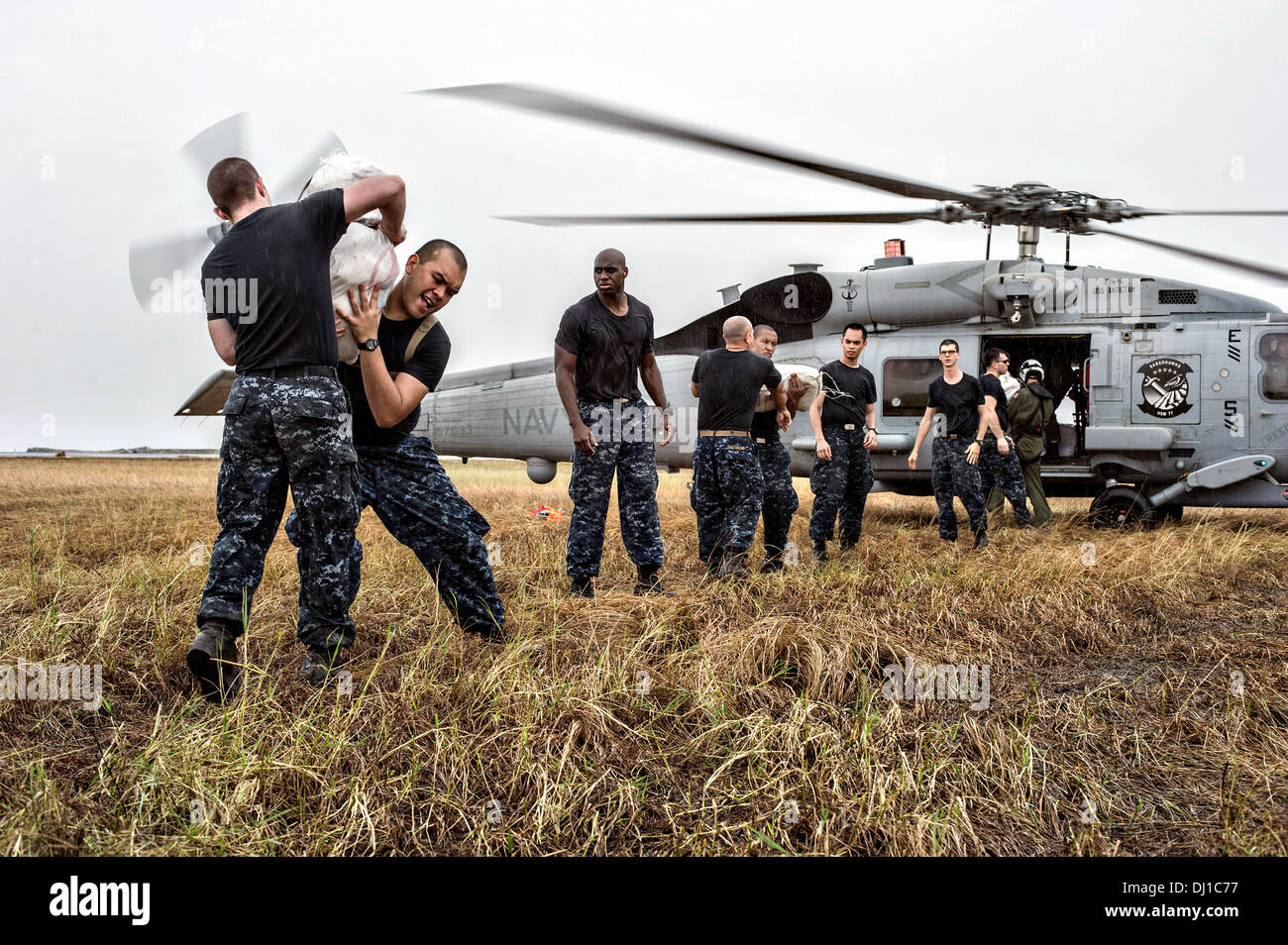 US Navy Matrosen bilden eine Linie, Hilfsgüter auf eine MH-60R Seahawk zur Verteilung an abgelegenen Dörfern in der Nachmahd des Super Taifun Haiyan 17. November 2013 in Tacloban, Philippinen zu laden. Stockfoto