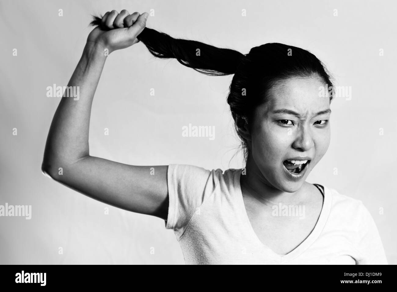 Porträt des einsamen jungen Frau ziehen ihr Haar sieht frustriert, schwarz / weiß Stil Stockfoto
