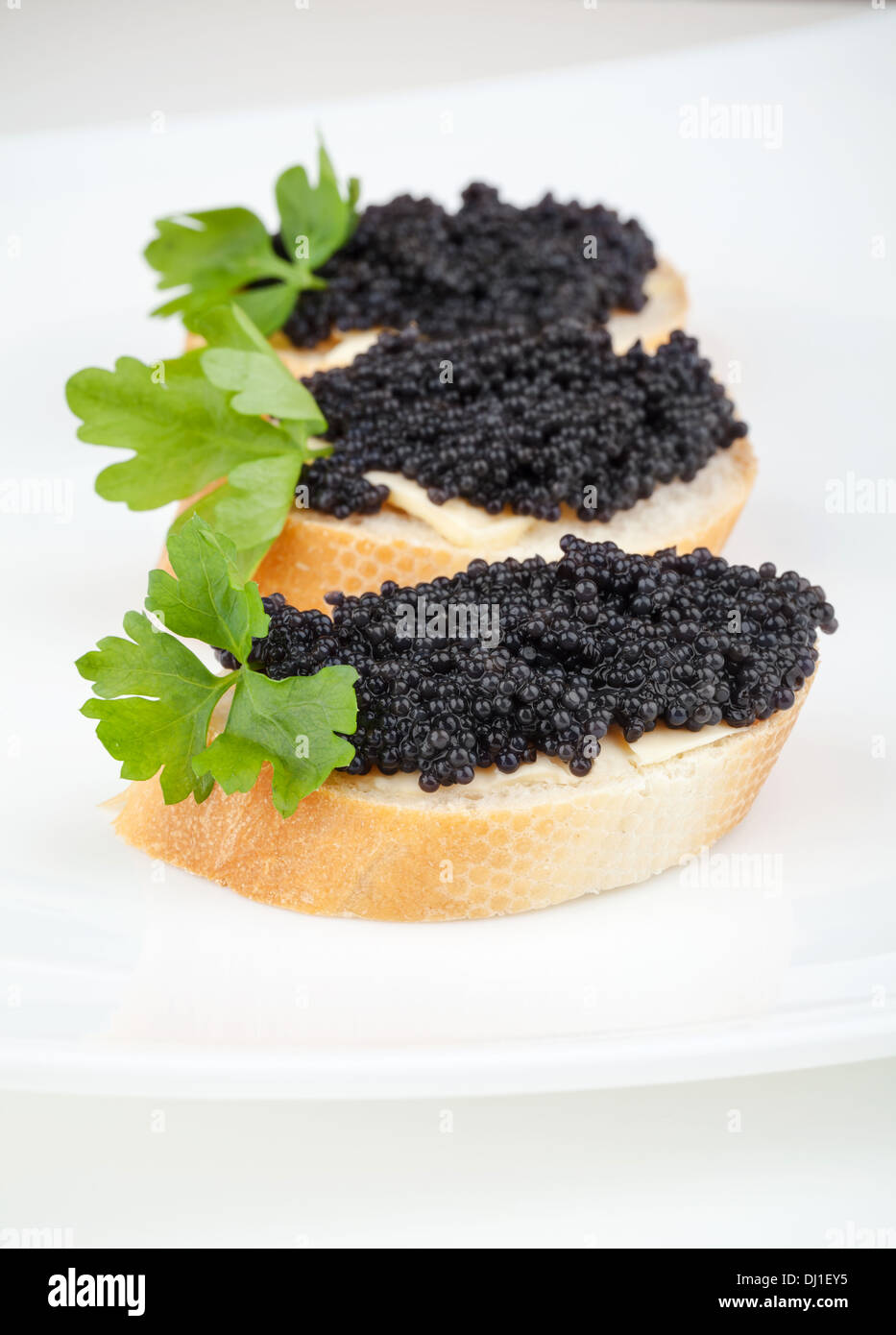 Kleine Sandwiches mit schwarzem Kaviar auf weißen Teller Stockfoto