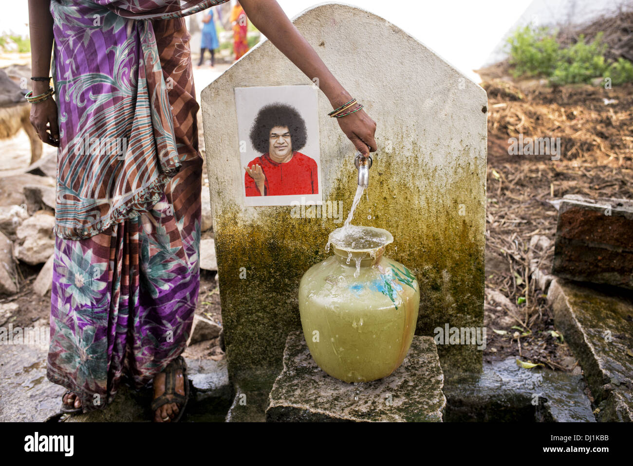 Indische Frauen einen Plastiktopf mit Wasser aus einem Standrohr in einem indischen Dorf Straße zu füllen. Andhra Pradesh, Indien Stockfoto