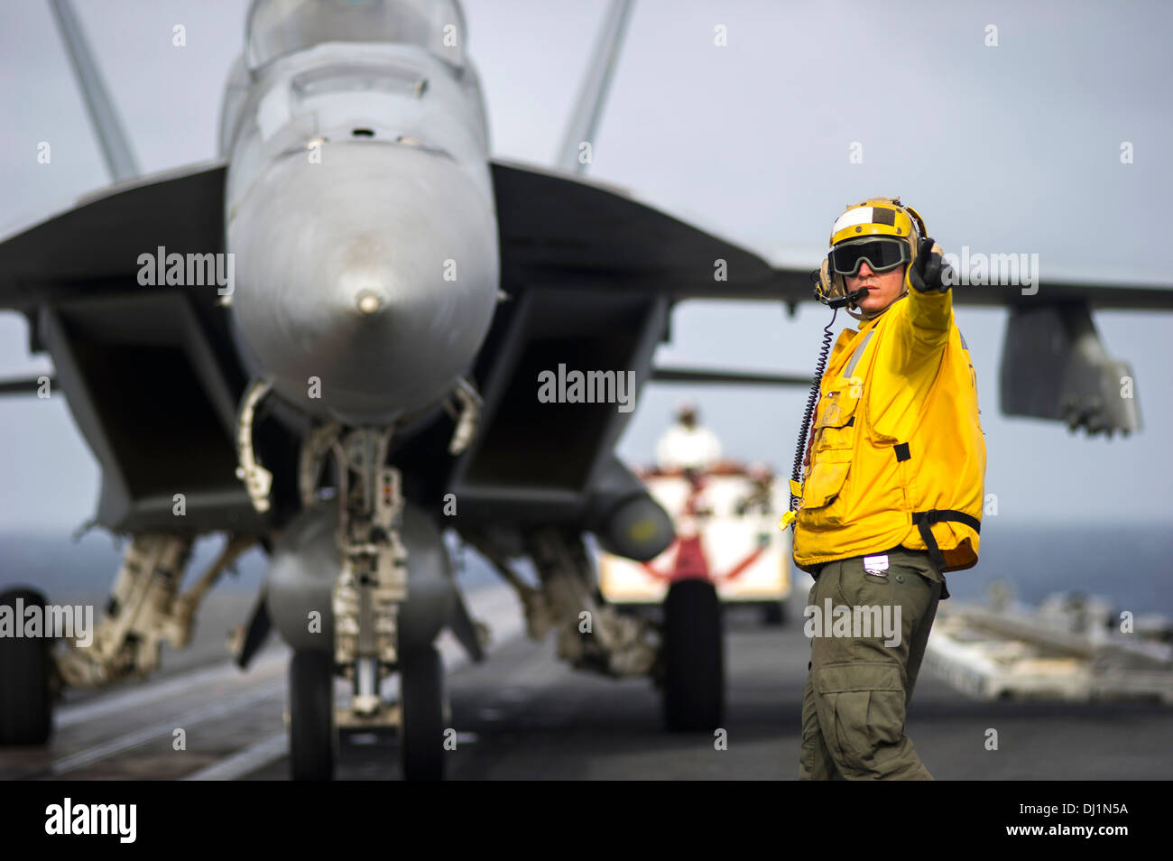US Navy Matrosen signalisiert der Pilot einer F/A-18 Super Hornet-Kampfflugzeuge auf dem Flugdeck des Flugzeugträgers USS George Washington 5. November 2013 in das Südchinesische Meer tätig. Stockfoto