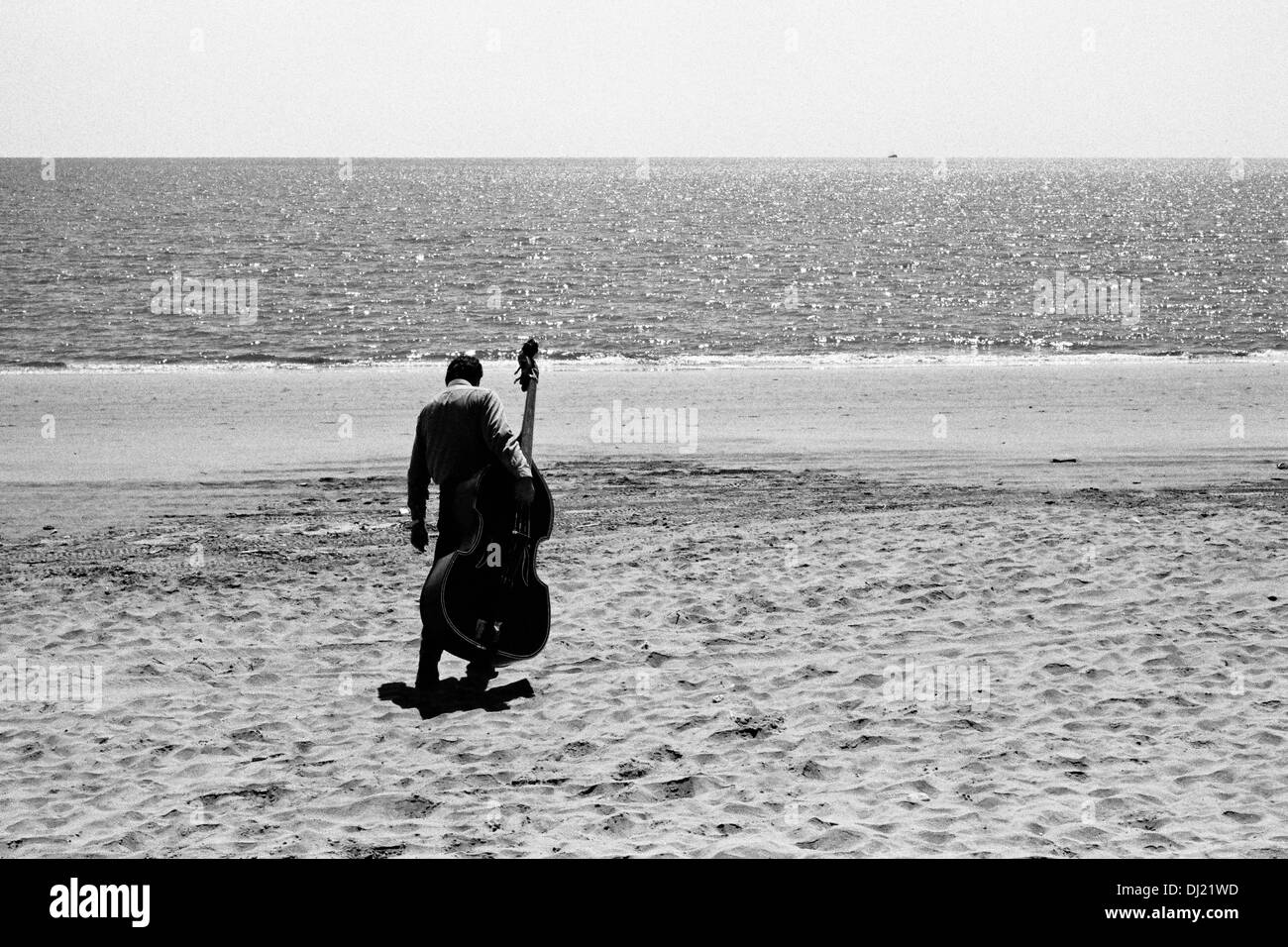 Ein mexikanische Musiker aus eine Mariachi-Band trägt seinen Kontrabass am Strand von Los Mochis, Mexiko. Stockfoto