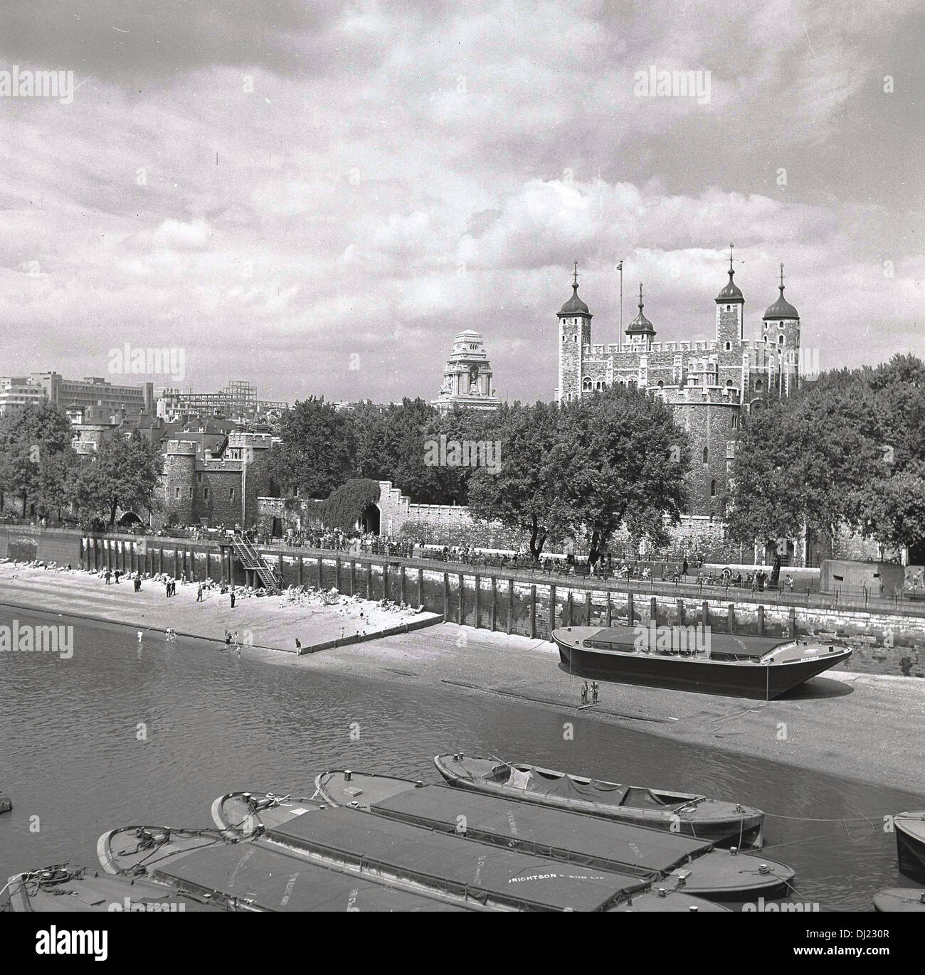 1950er Jahren und ein historisches Bild aus dem ganzen der Themse zeigt die berühmte Tower of London und Lastkähne festgemacht, auf dem Wasser. Stockfoto