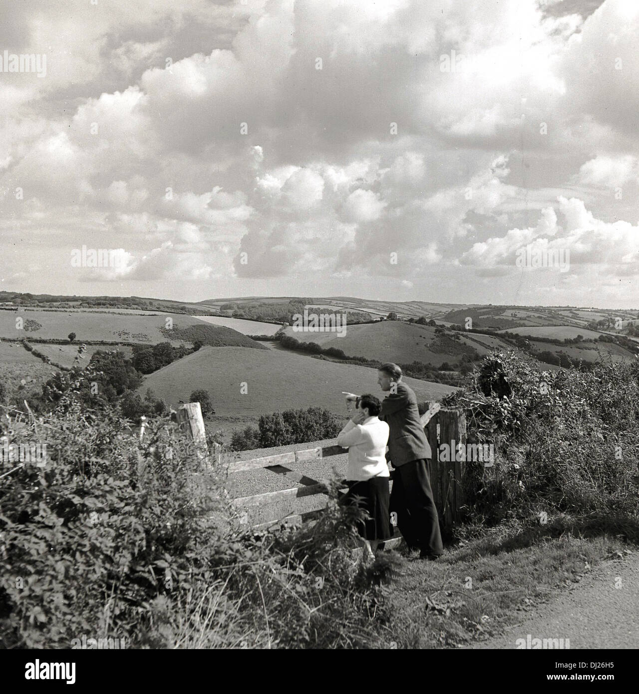 1950er Jahren und ein historisches Bild von ein paar tatenlos einen Hof, die Landschaft und die Landschaft zu bewundern. Stockfoto