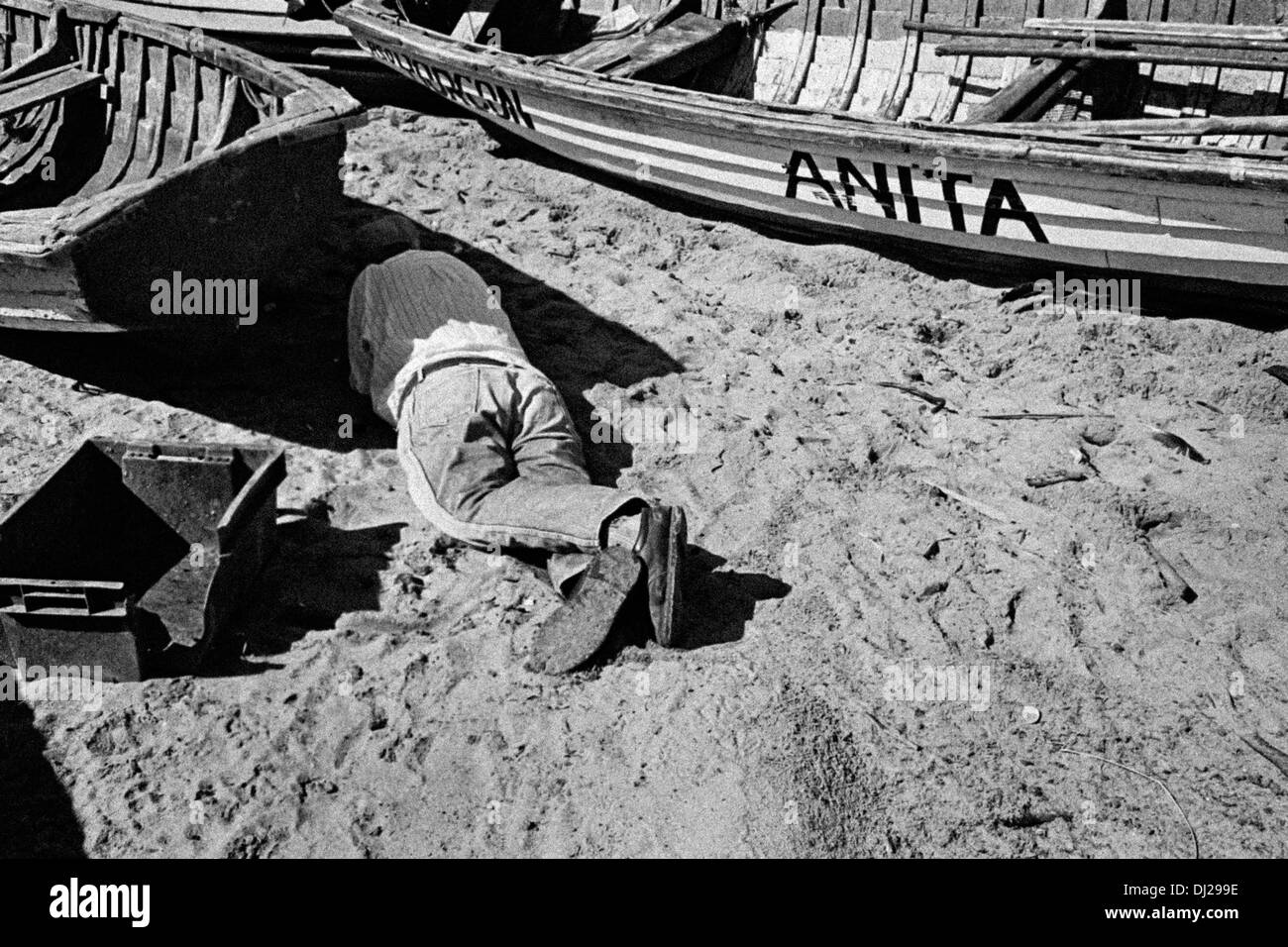 Ein chilenischer Fischer, ruht nach dem Trinken ein paar Pisco Aufnahmen im Schatten seines Bootes am Strand Quintero, Chile. Stockfoto