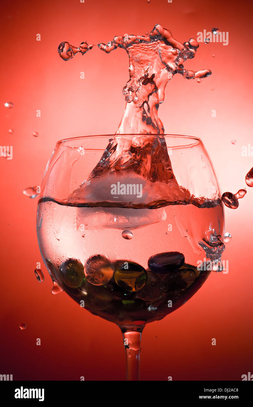 Spritzer kaltes Getränk auf lebendige roten Hintergrund Stockfoto